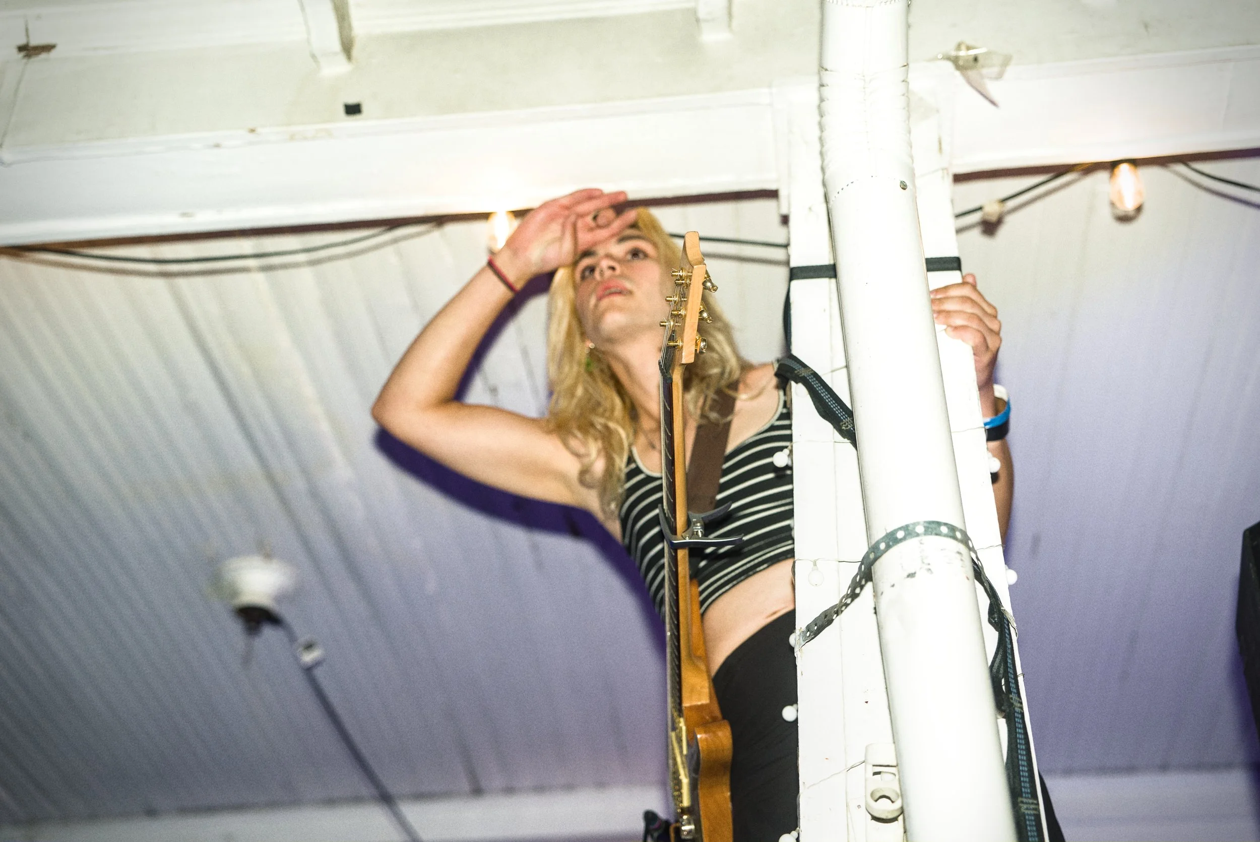 A woman with blonde hair and a black-and-white striped top examining equipment on a white structure in an industrial setting.