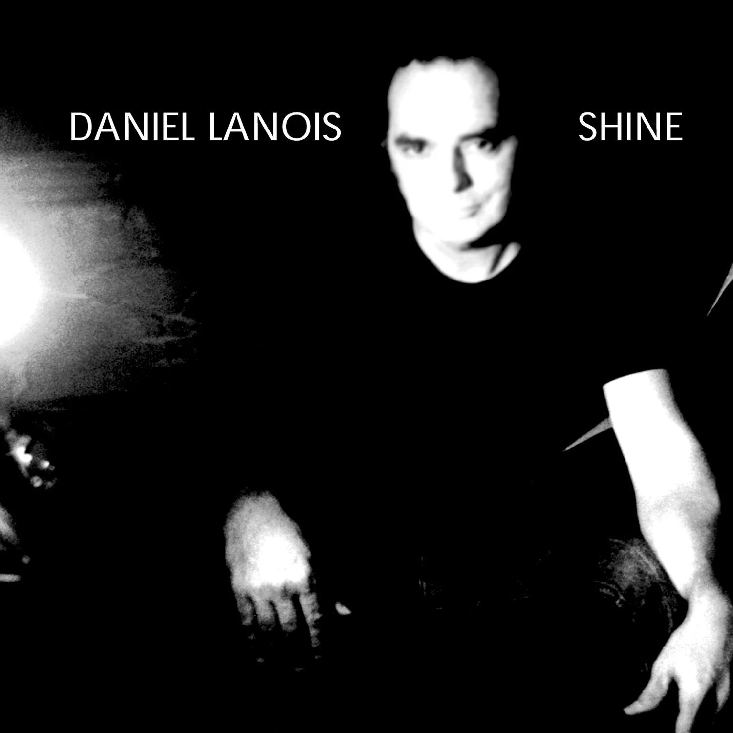 Black and white album cover featuring a man with short hair wearing dark clothing, with text 'DANIEL LANOIS' on the left and 'SHINE' on the right.