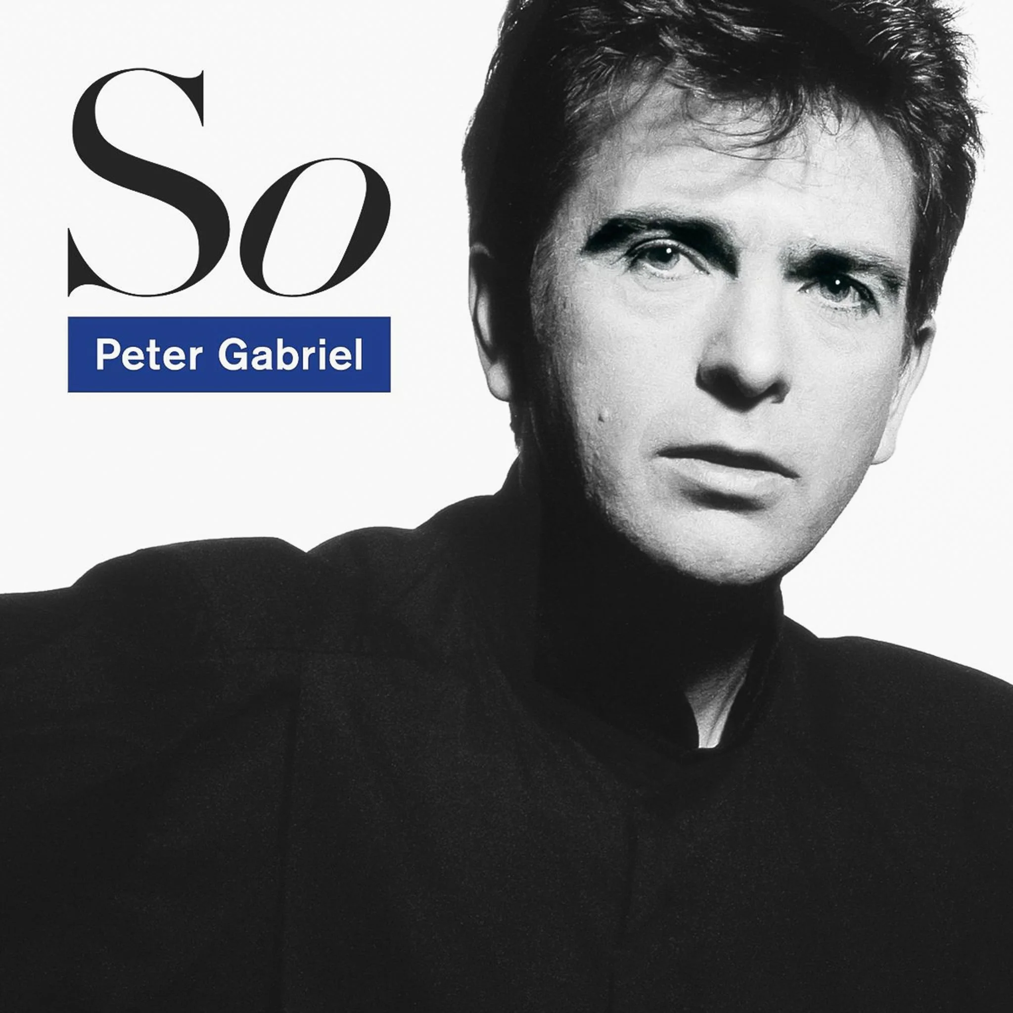 Black and white album cover featuring a close-up of a man with dark hair, wearing a high-collared black shirt, with text indicating the album 'So' by Peter Gabriel.