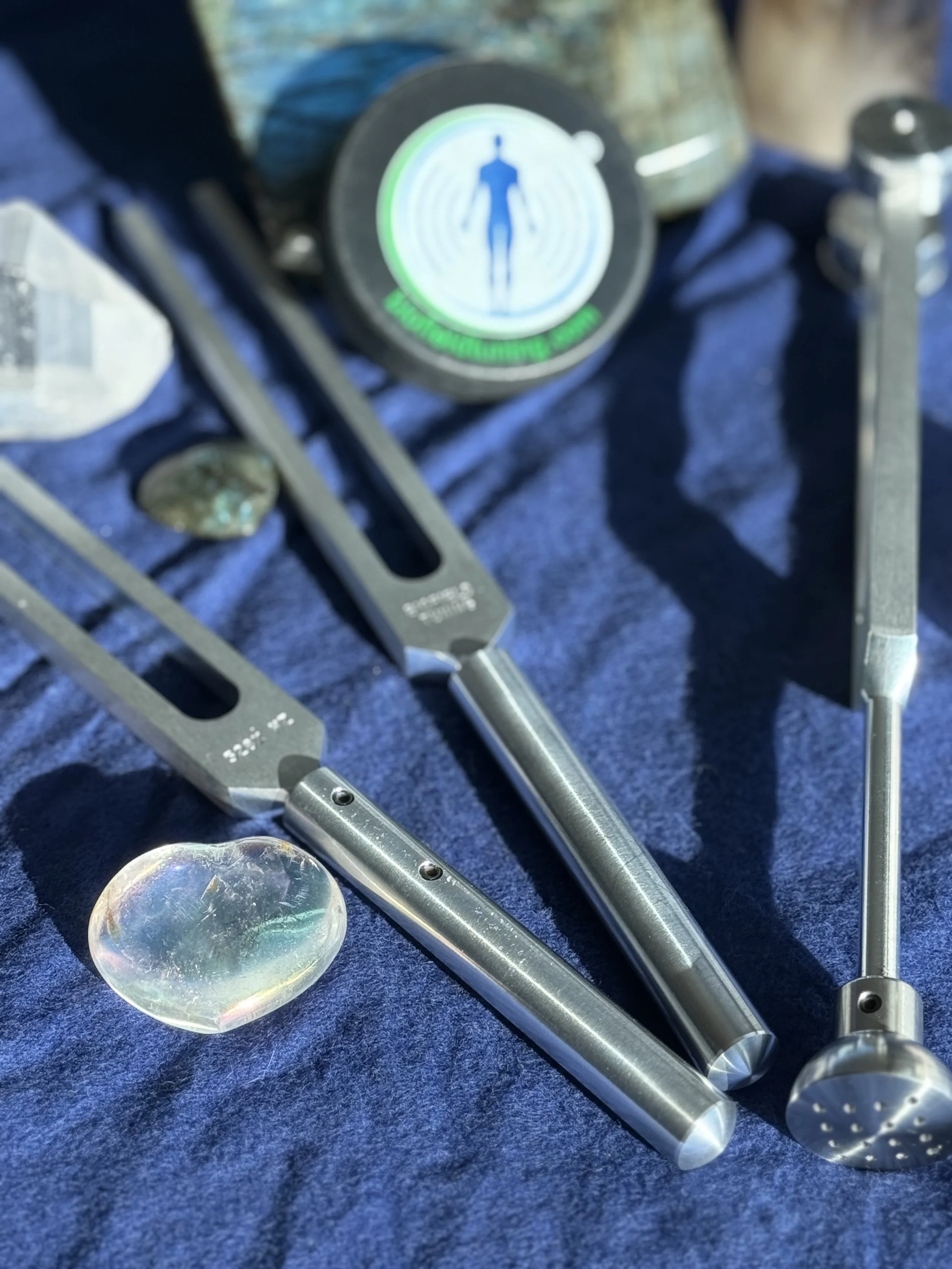 Various surgical or medical instrument tools laid out on a dark blue cloth, with a glowing circular sign featuring a human body outline in the background.