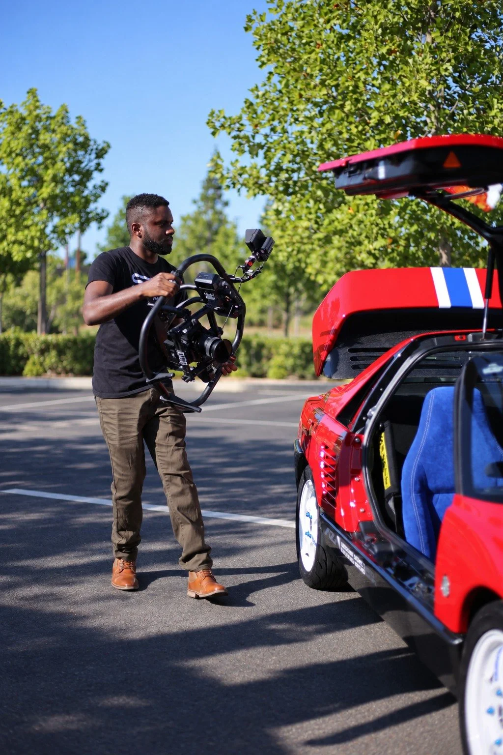 Shane Smith filming a red sports car with a professional camera rig.