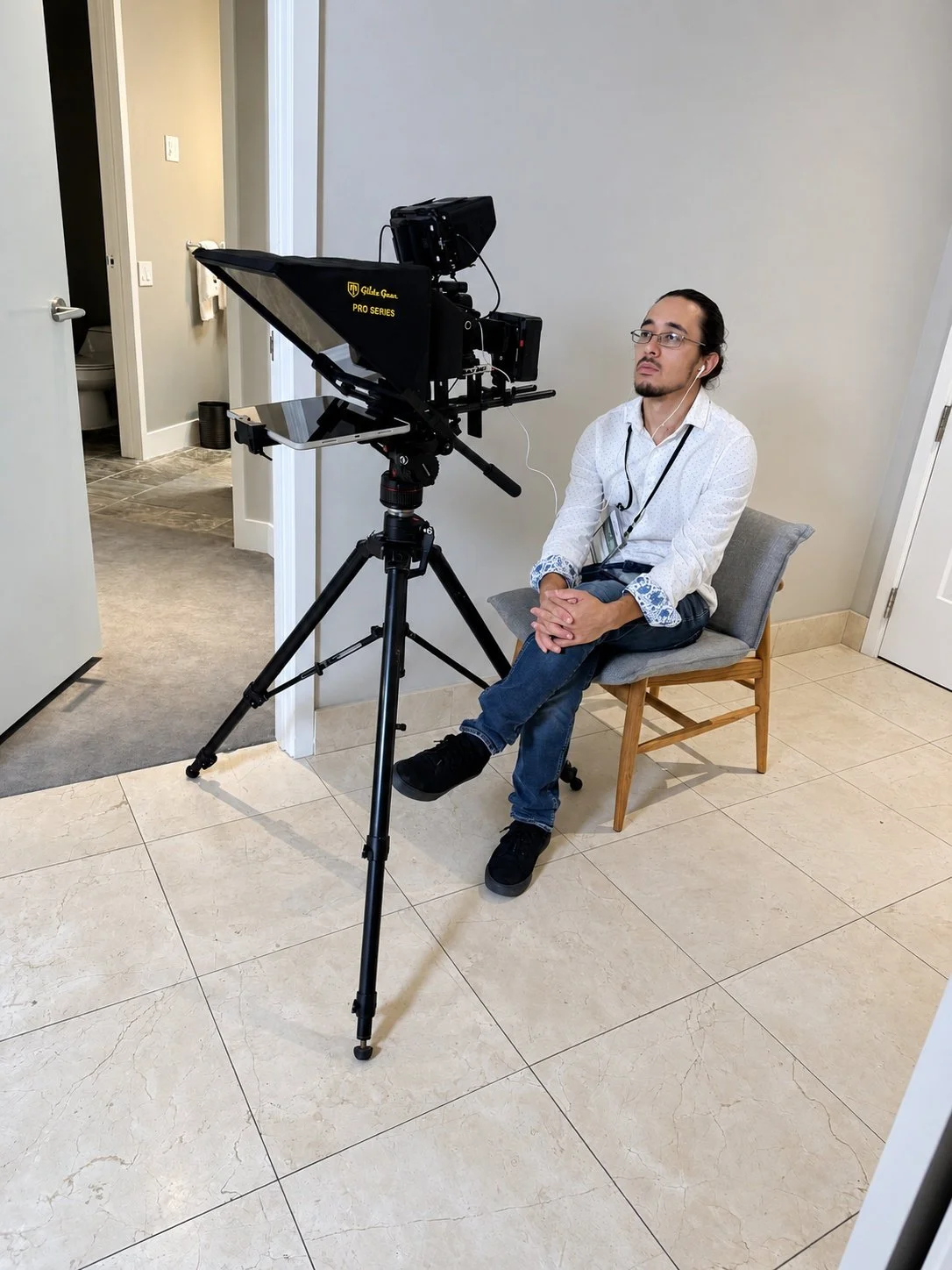 A seated interview subject in front of a professional camera and teleprompter.