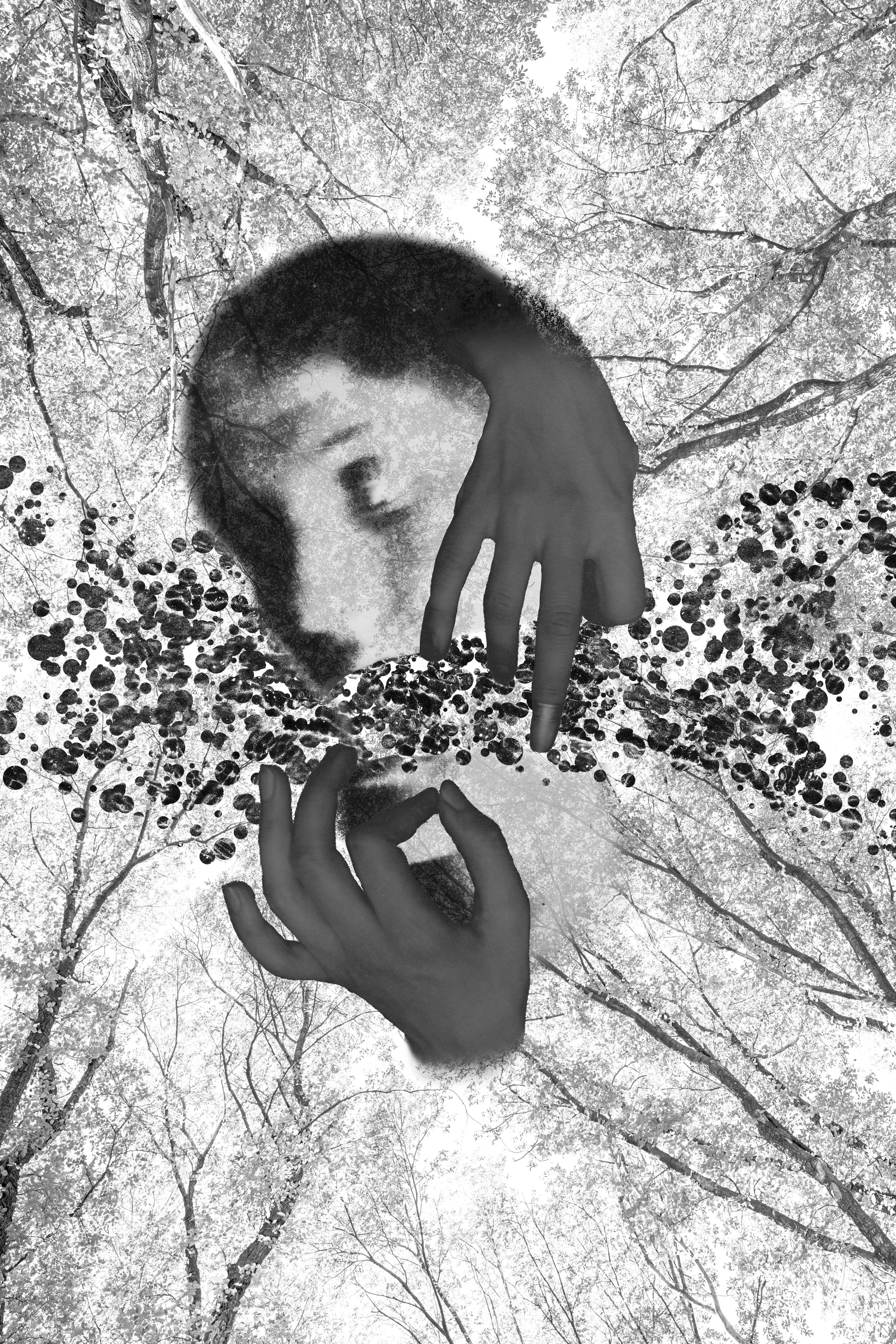 A person with long hair and a hood, making a peace sign with one hand, surrounded by tree branches and leaves in a monochrome or negative image effect.