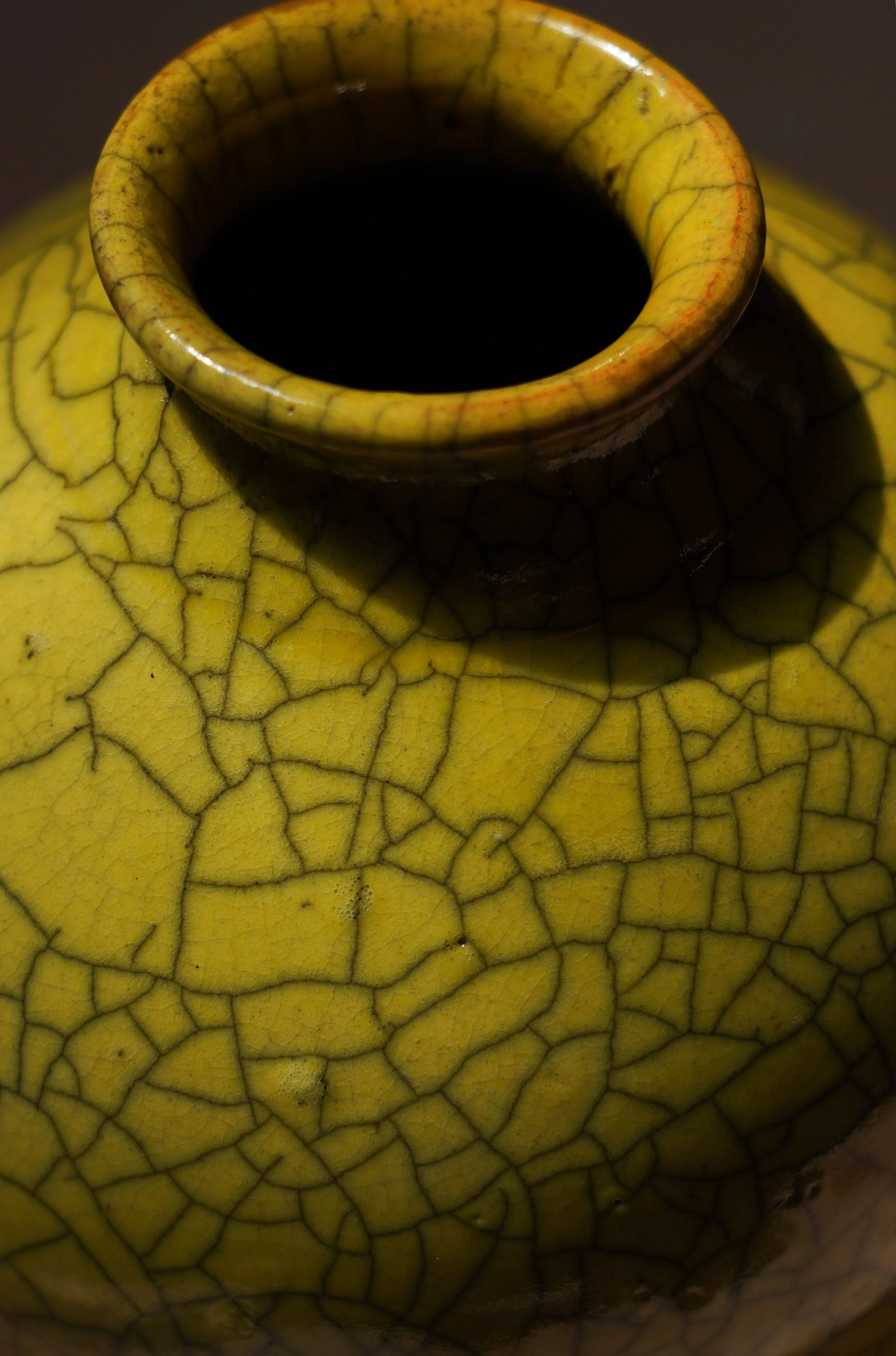 Close-up of a yellow ceramic vessel with a crackled glaze pattern.