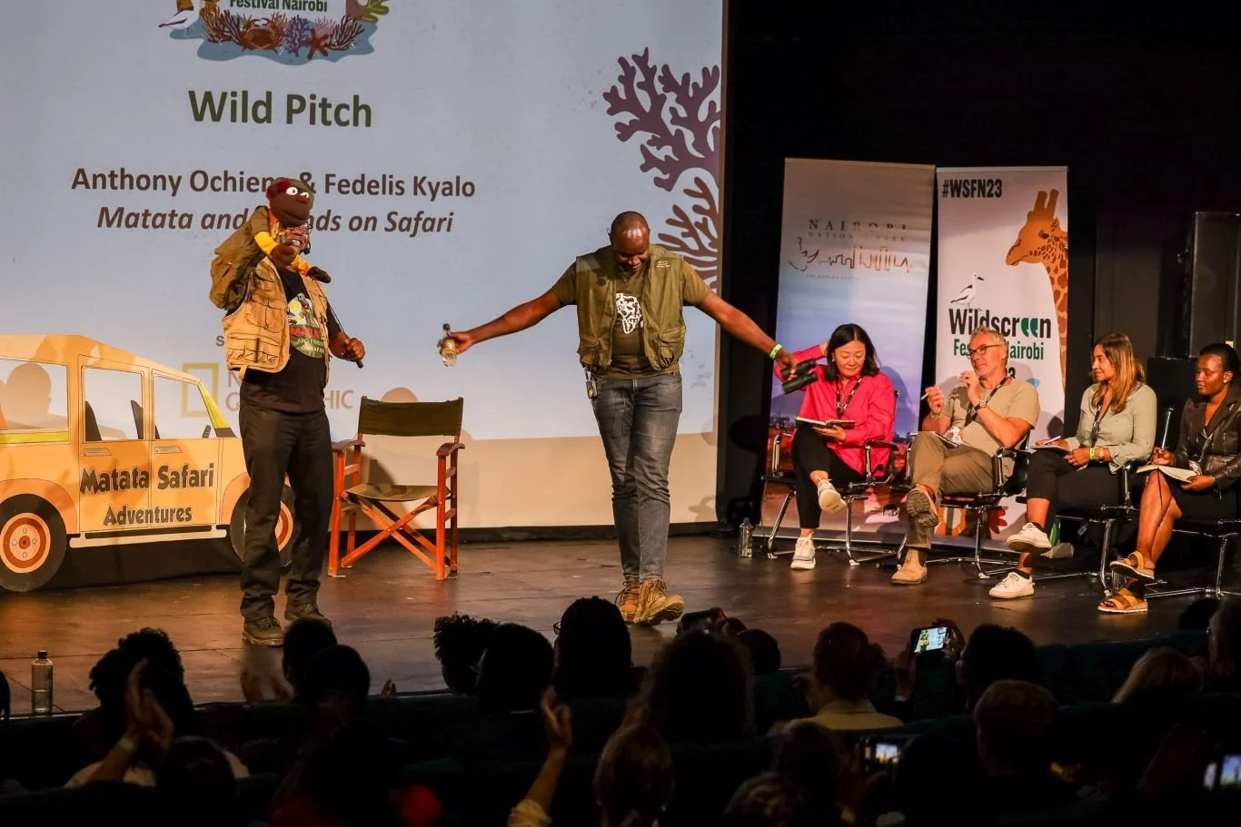 A panel discussion at an event called Wild Pitch during Wildscreen Nairobi, featuring a presentation about 'Matata and Friends on Safari' with people on stage, one holding a puppet and others seated.
