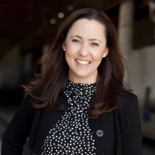 Listing agent Megan Spargo-Ferrell, with shoulder-length brown hair smiling in an outdoor location.