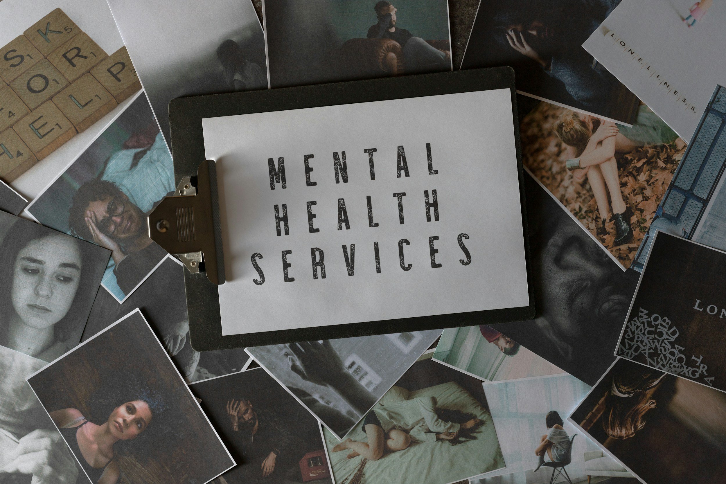 A collection of photographs surrounding a clipboard with a paper titled 'MENTAL HEALTH SERVICES', featuring images of diverse individuals in various emotional states.