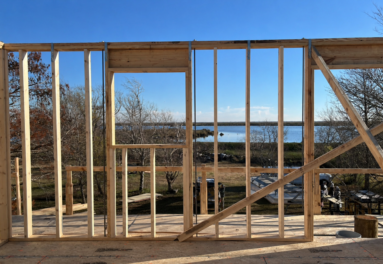 Wooden framing for a house under construction with a scenic view of a river and trees in the background.