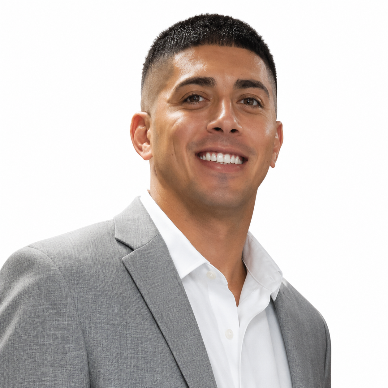 A smiling man wearing a light gray suit jacket and white dress shirt, posing against a plain white background.