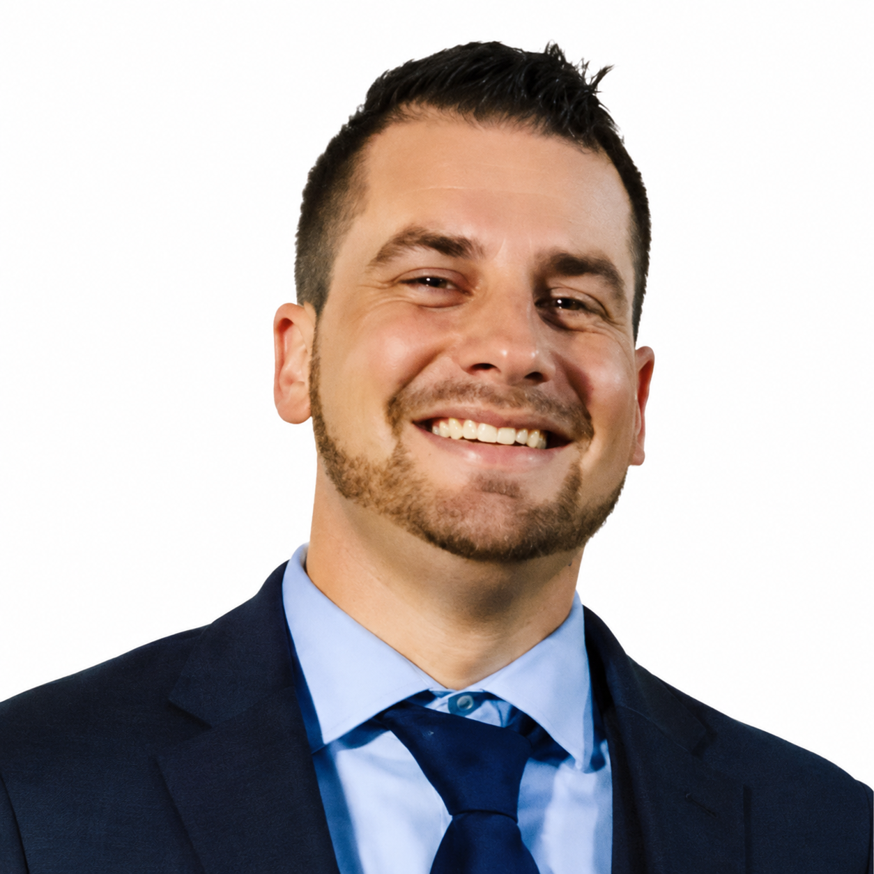 A smiling man in a navy suit, light blue shirt, and dark blue tie against a white background.