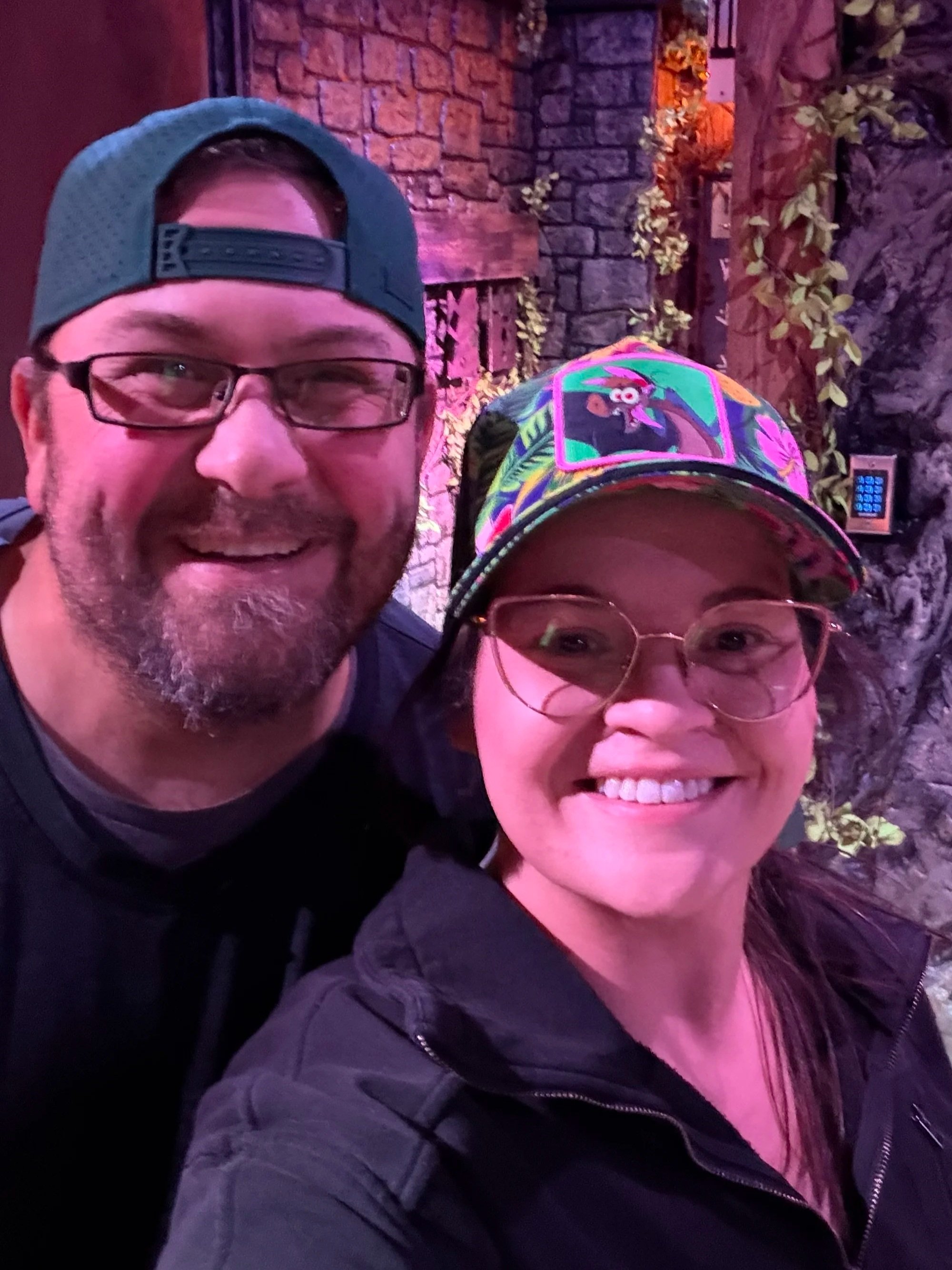 two people smile at the camera both with hats