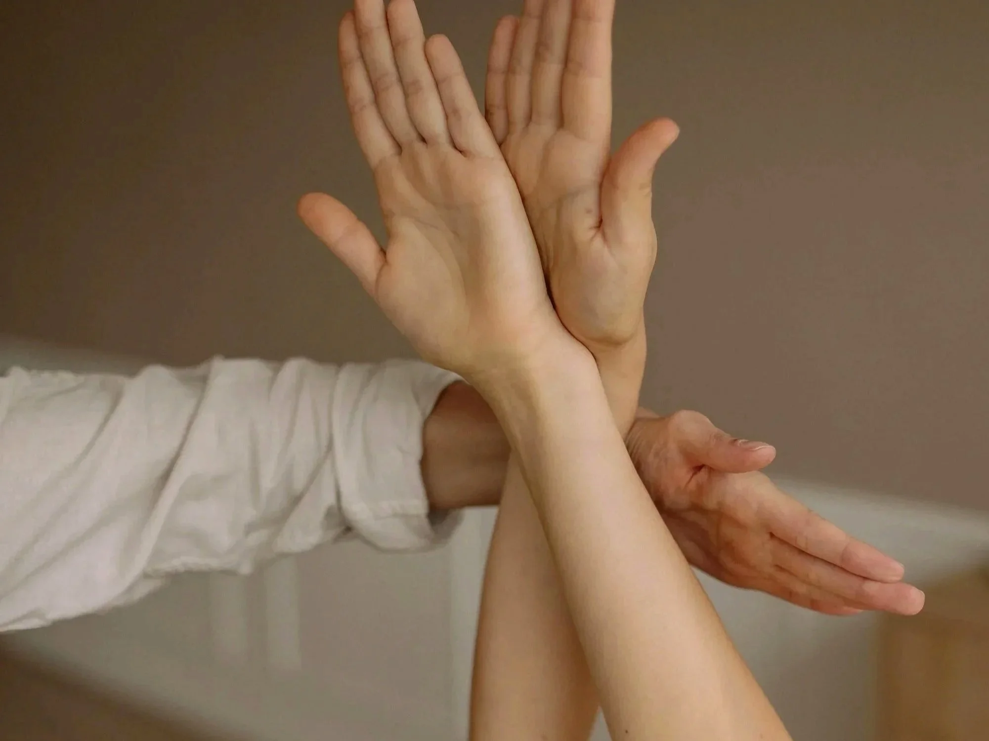 Two sets of hands, one older and one younger, clasped together in a gentle gesture.