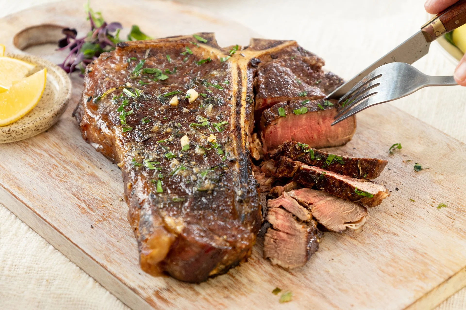 Maple and garlic glazed T-bone steak, sliced on a wooden board