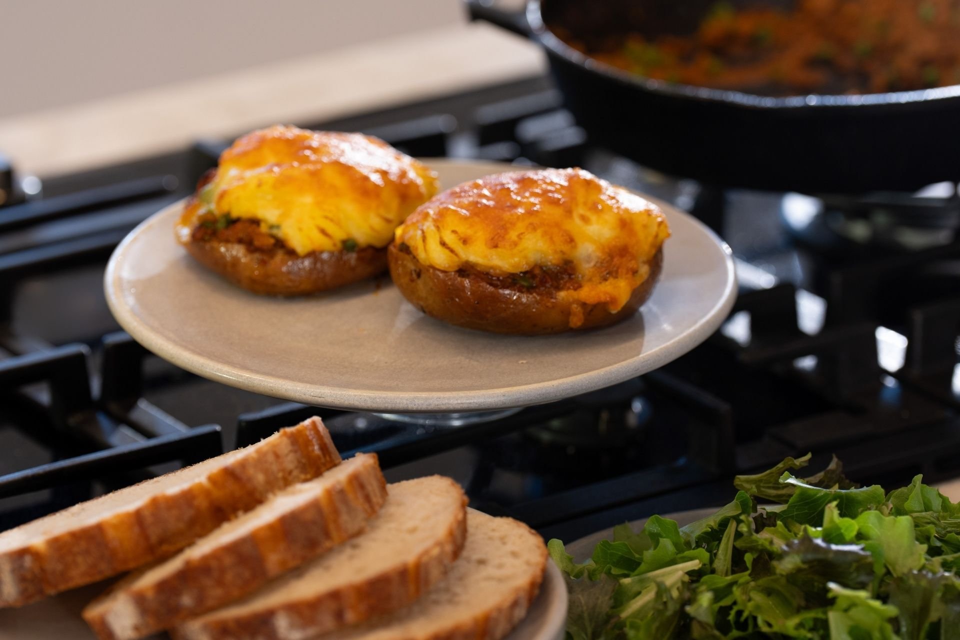 Shepherds pie jacket potatoes by Carlita Campbell, served on a plate beside sliced bread