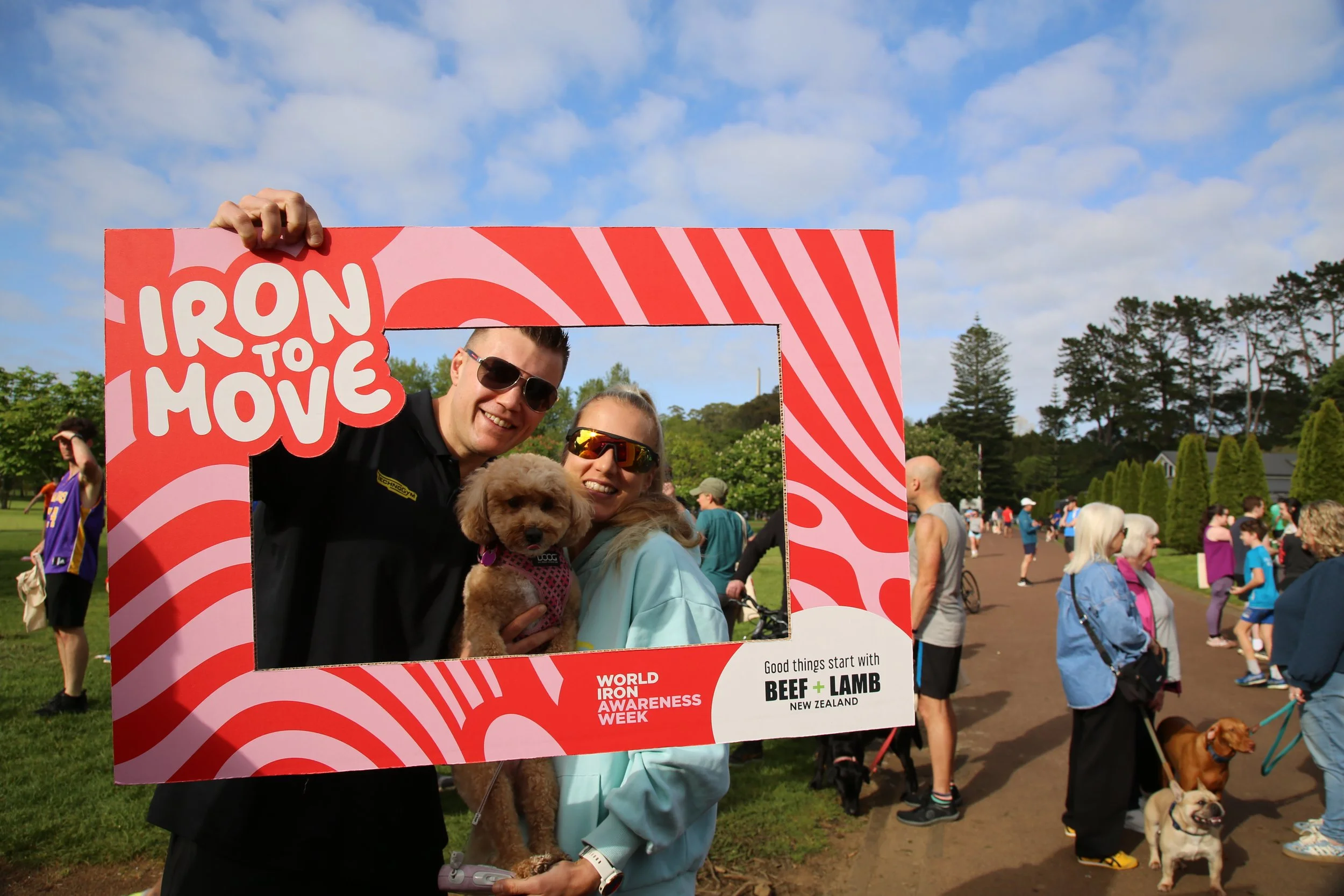 Handsome couple plus their dog holding a red and pink sign that says Iron to Move