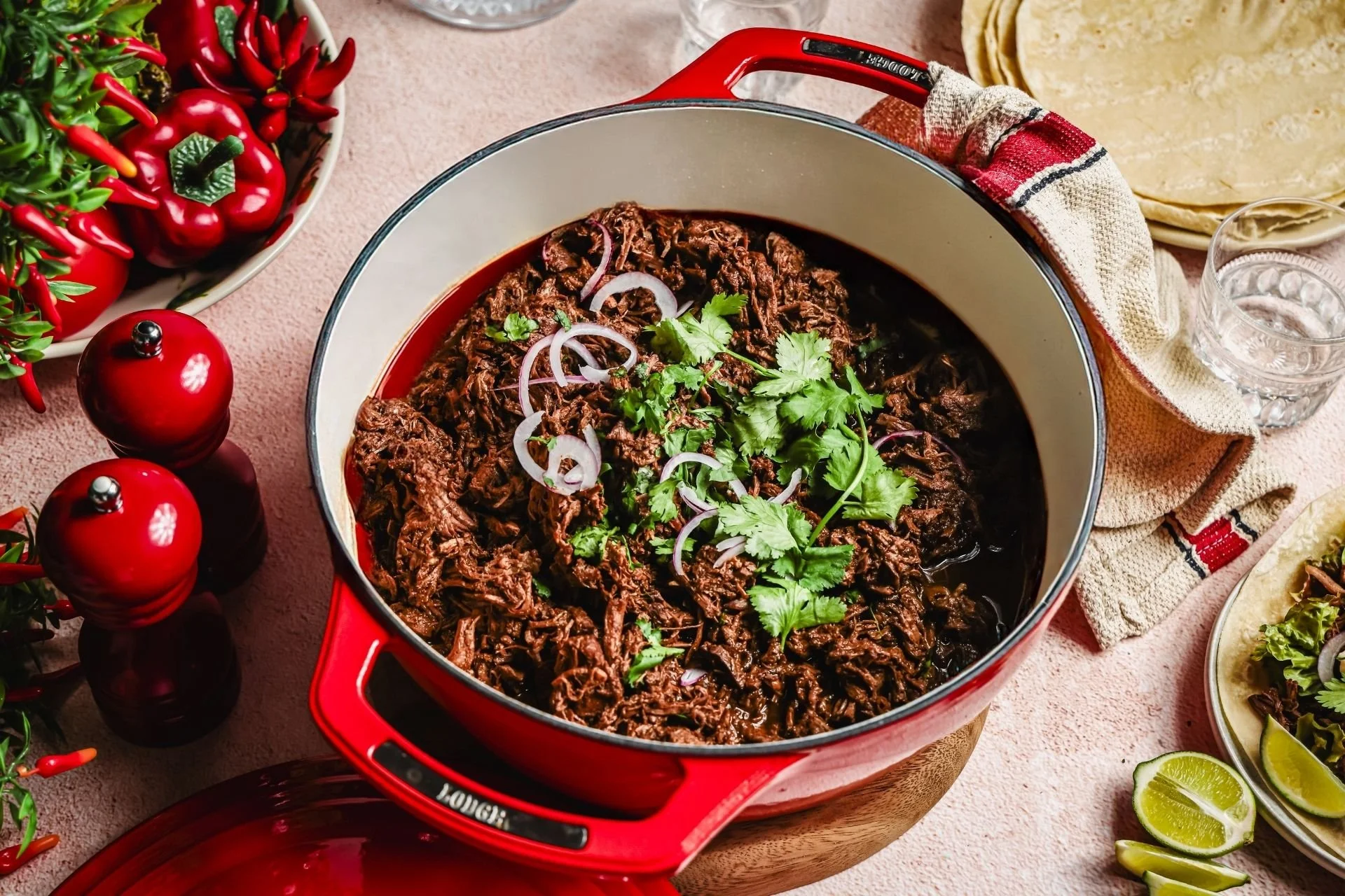 Slow-cooked beef barbacoa shredded beef chuck steak topped with fresh coriander and sliced red onion, served with tortillas, lime wedges and fresh chillies.