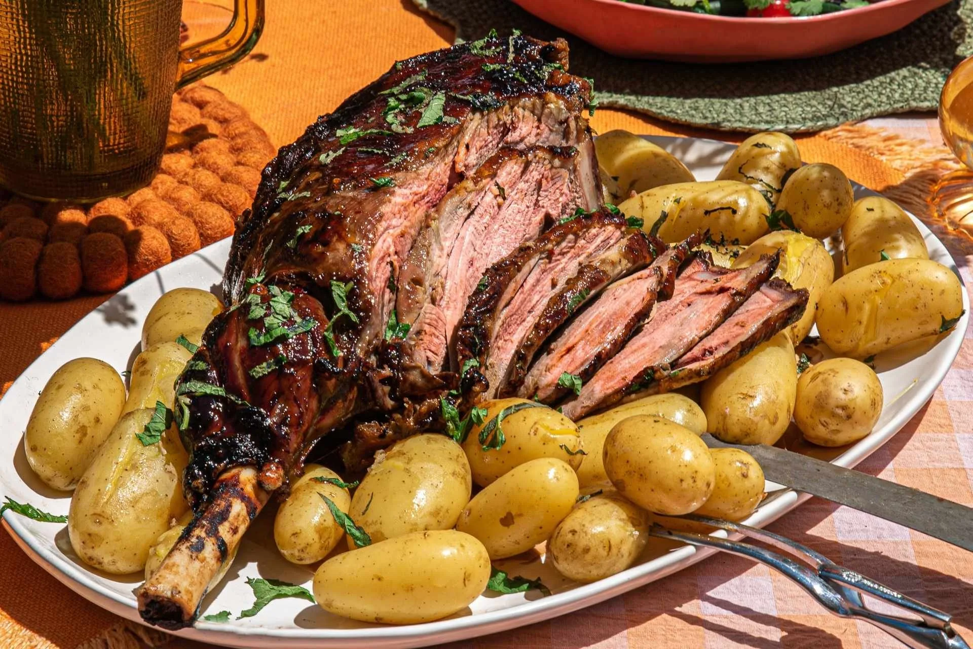 Sliced roast leg of lamb with baby potatoes