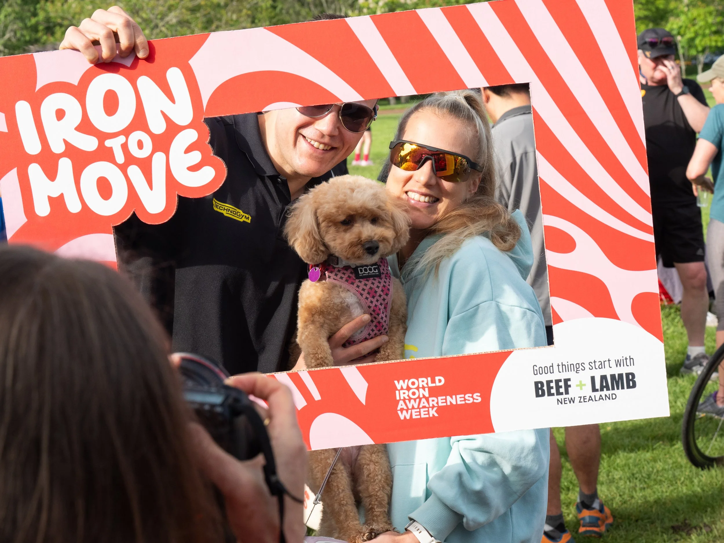 Couple and their dog posing with an Iron to Move photo frame at the World Iron Awareness Week 2025 parkrun