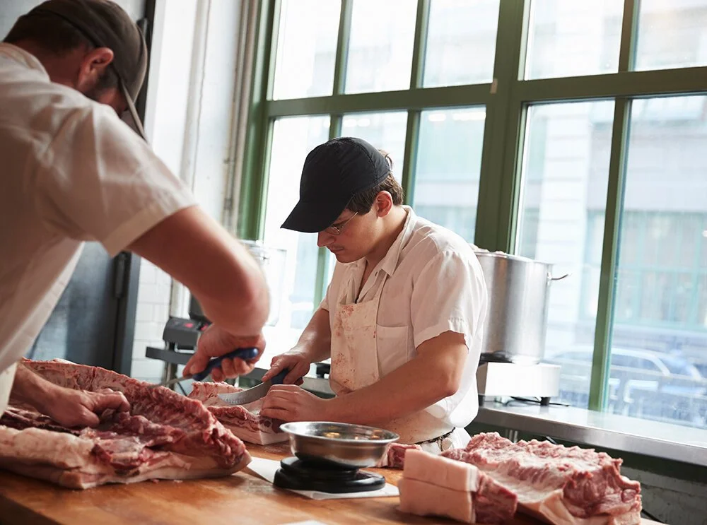 Butchers cutting and preparing meat in a butcher shop
