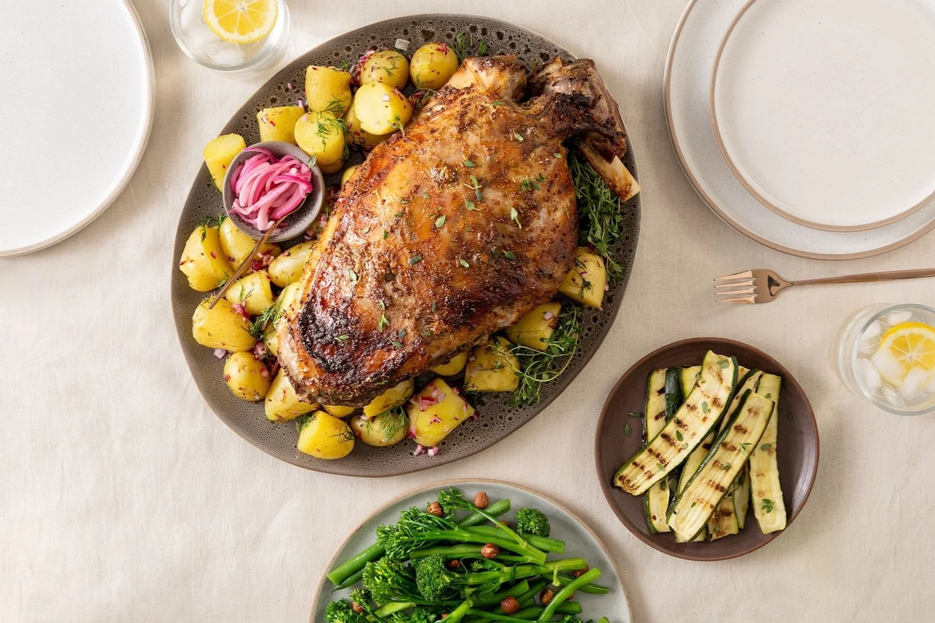 Roast lamb with potatoes, green beans and courgette on a shared table