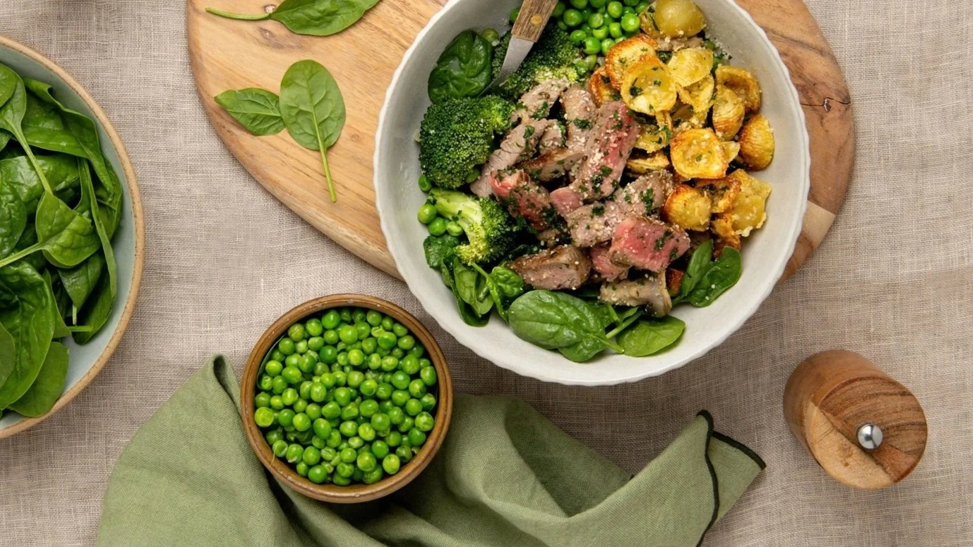 Sliced New Zealand beef steak served with crispy potatoes, broccoli, peas and fresh spinach, topped with chopped herbs.