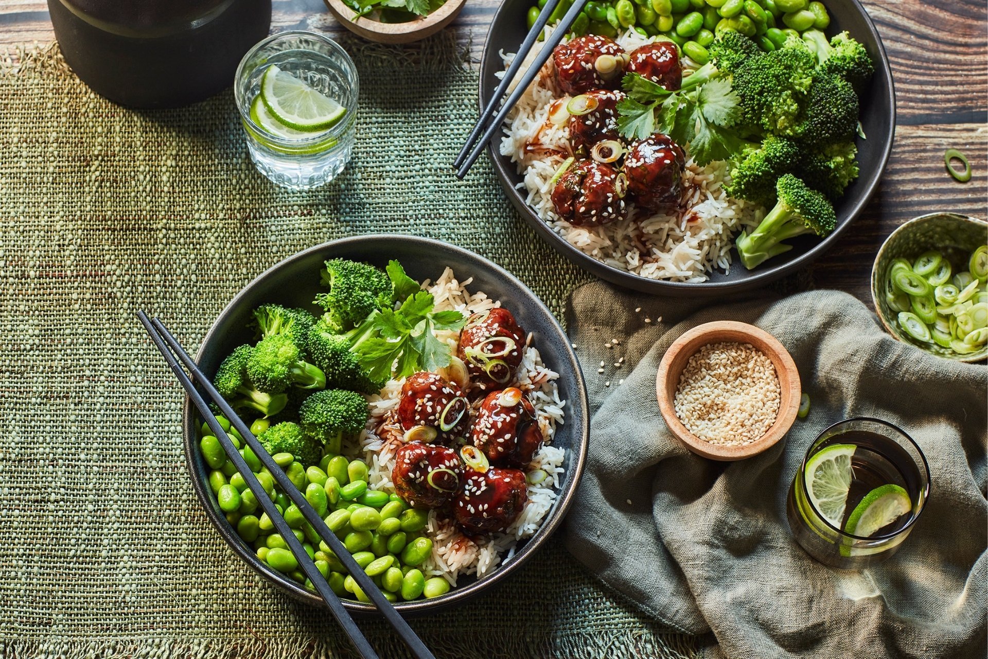 Sticky sesame lamb meatballs served with white rice, broccoli and edamame, topped with sesame seeds and spring onion.