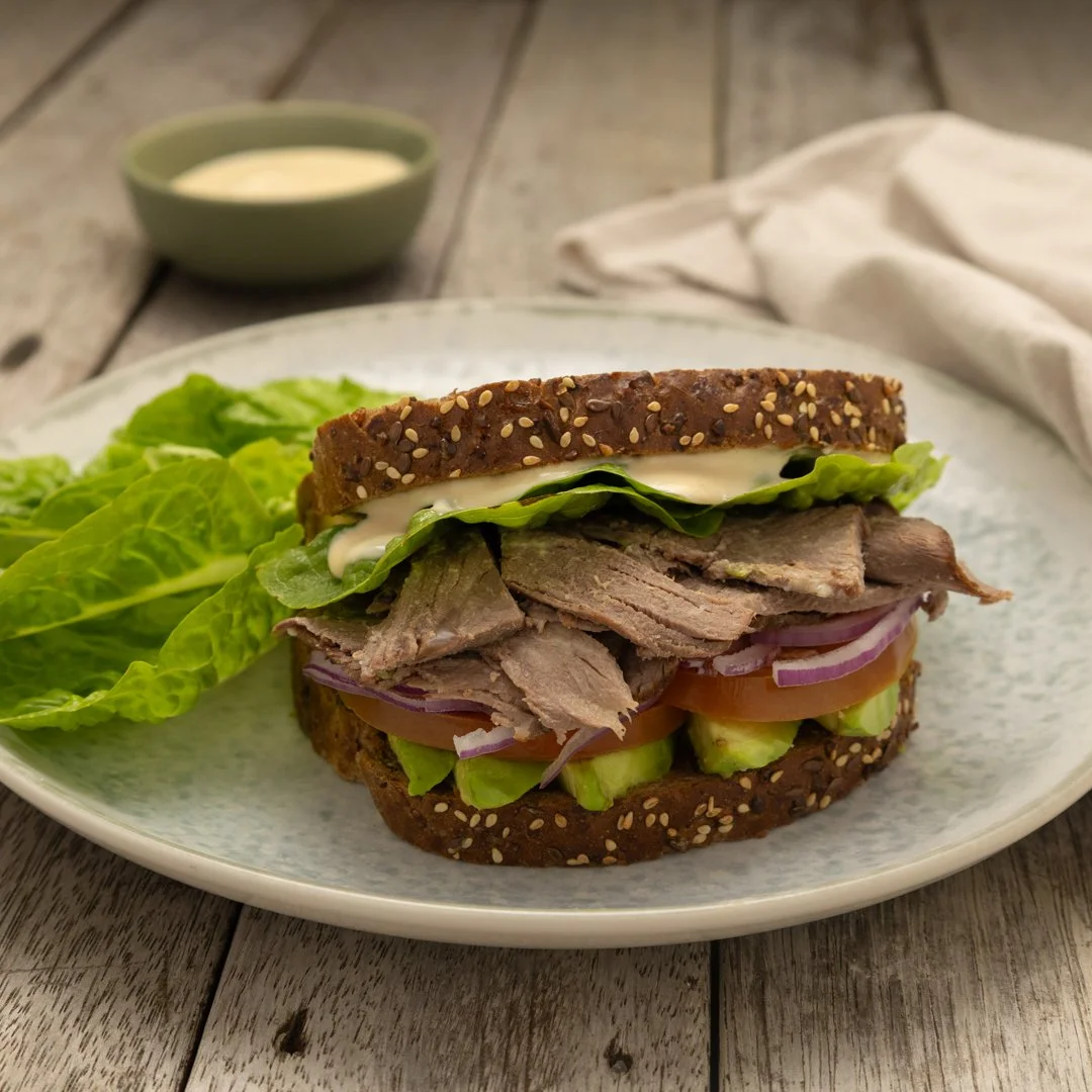 Leftover roast beef BLAT sandwich with sliced roast beef, lettuce, avocado, tomato, red onion and creamy dressing on seeded wholegrain bread.