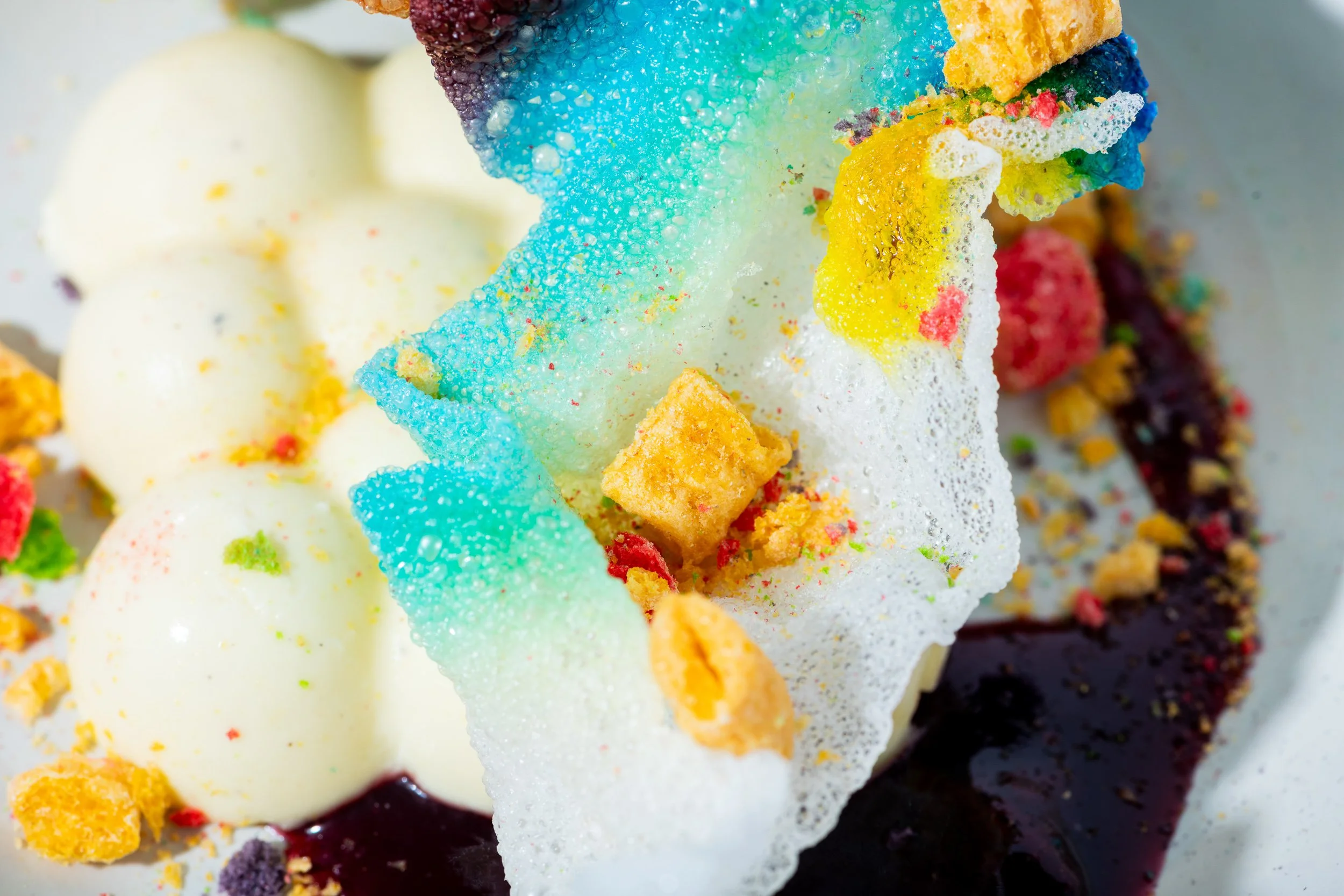 Deconstructed dessert with white spheres, blue sugar shard and multicolor garnishes, fine dining Kansas City

