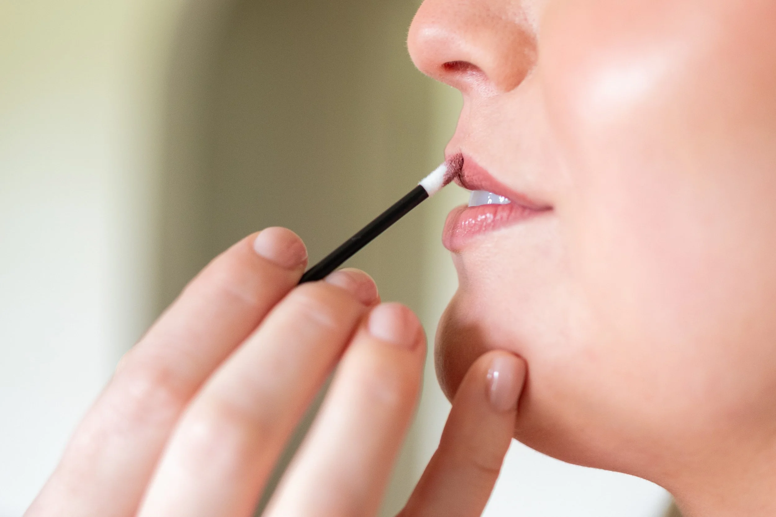 Close-up of a makeup brush applying product to a woman's lips