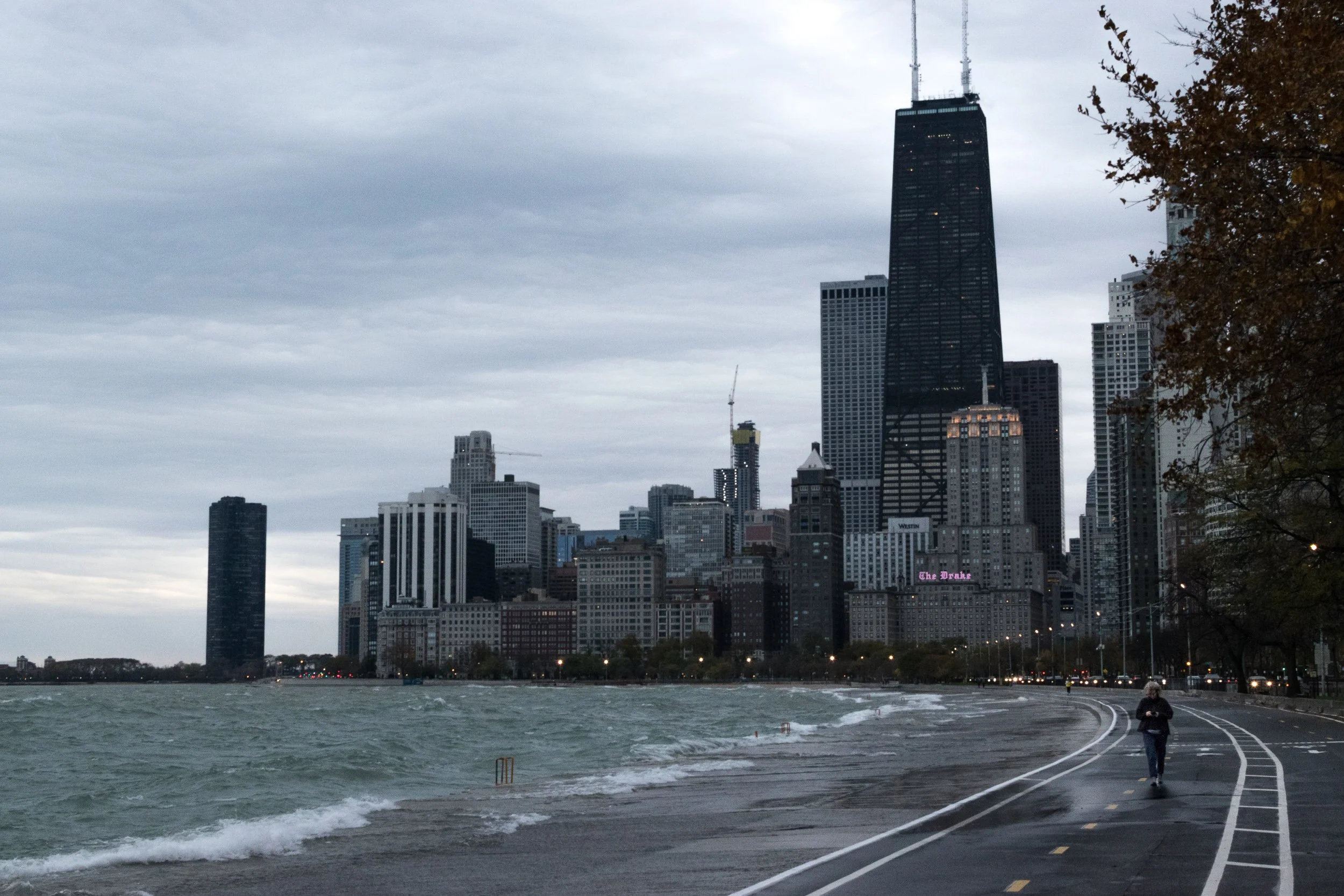 Lone runner on the Chicago lakefront path, overcast sky, city skyline receding in the background.