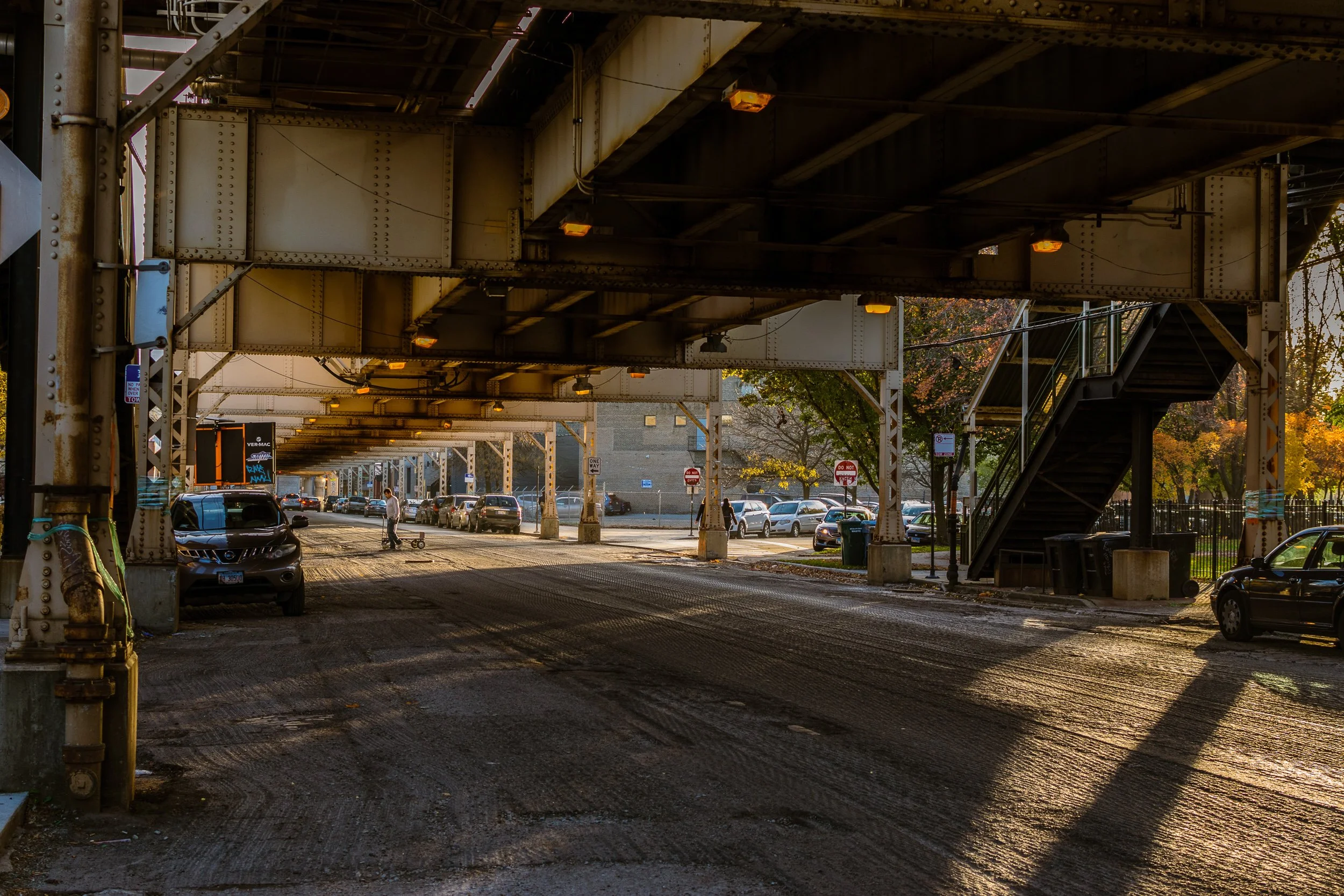 Under the Chicago elevated L train tracks, structural ironwork overhead, street scene below.
