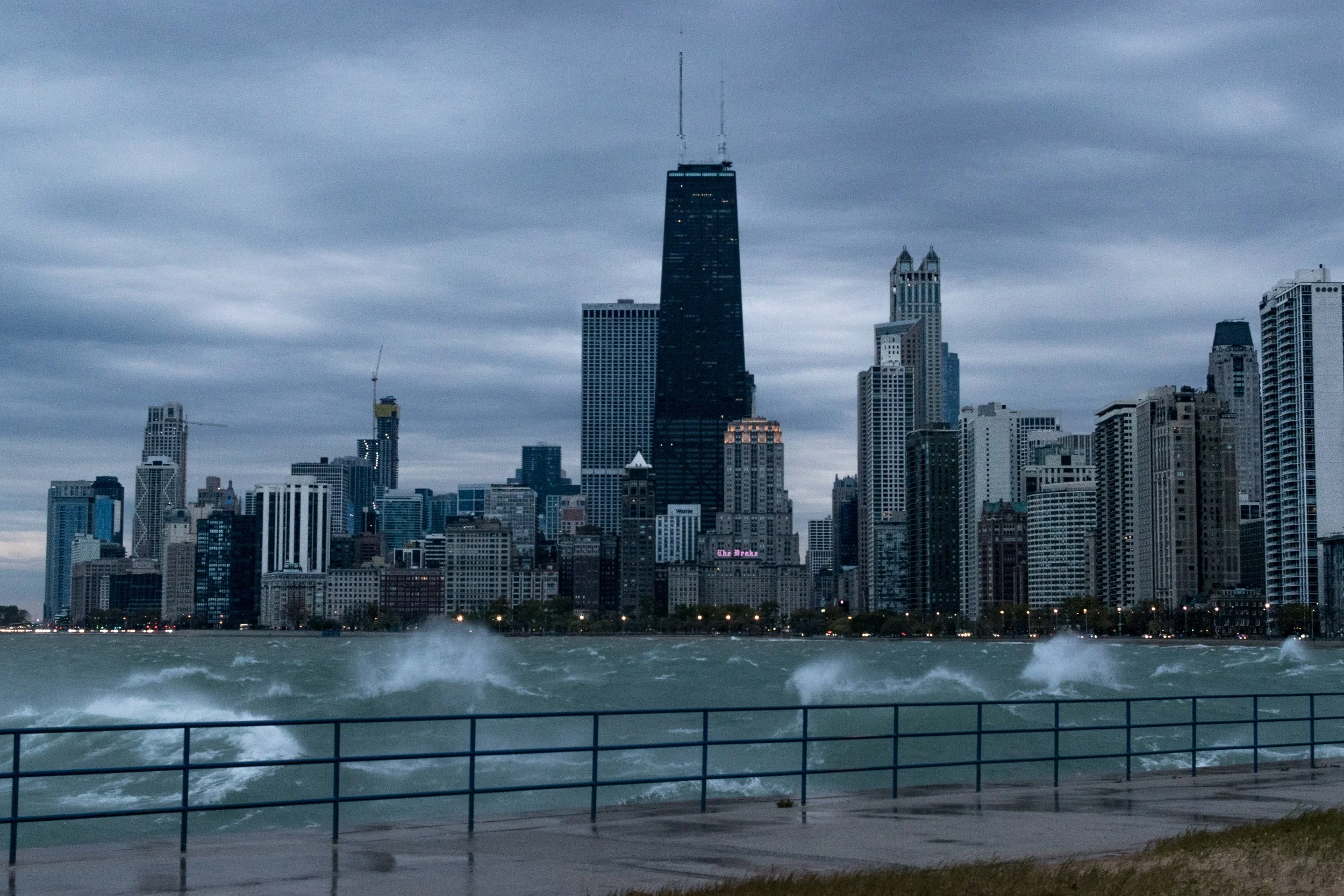  Chicago skyline in a storm from the lakefront, Hancock tower prominent, waves crashing the seawall.