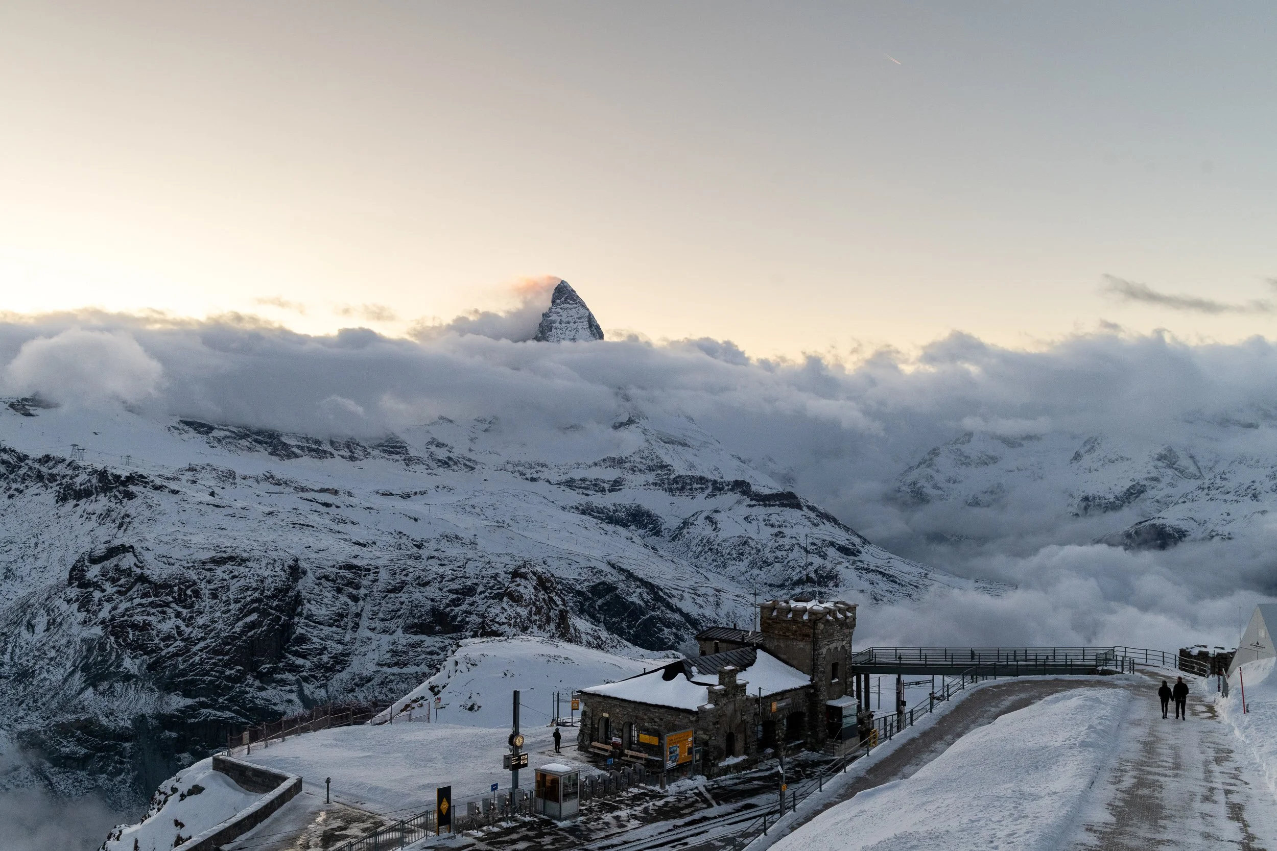 Matterhorn emerging above clouds in winter, Zermatt, Switzerland, ski lift station and walkway below.