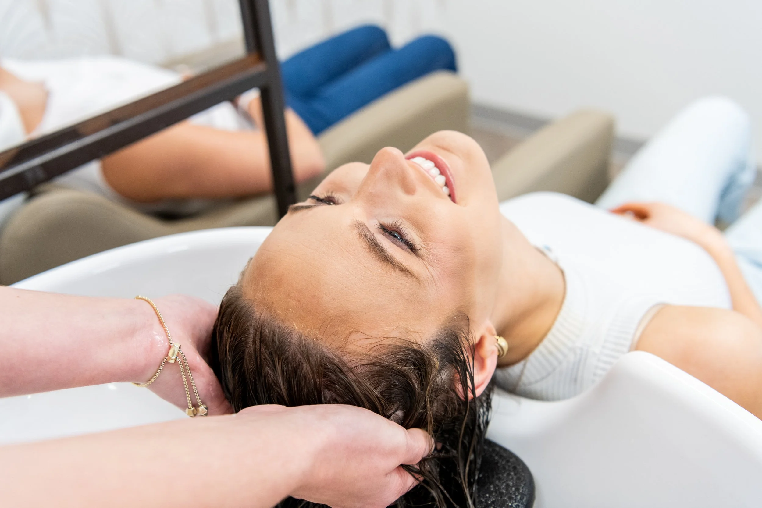 Woman smiling while receiving a hair wash at a salon basin