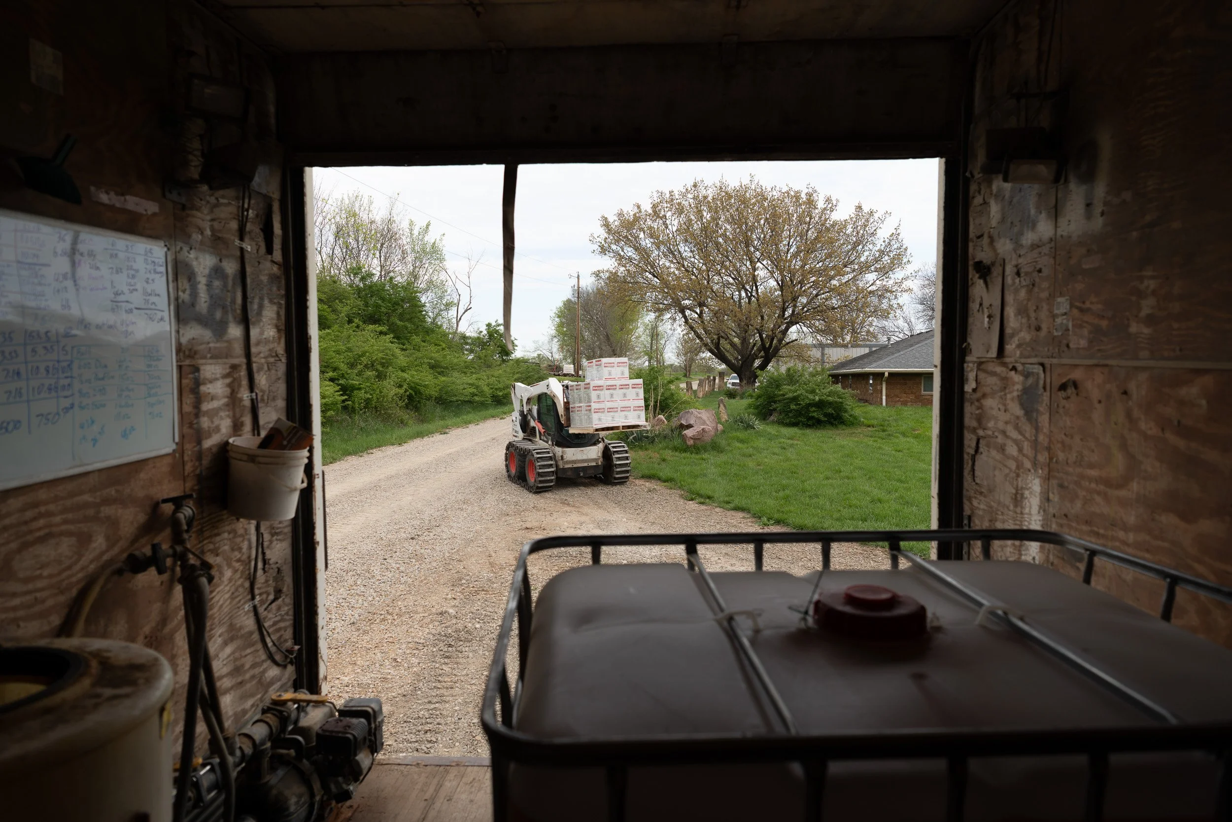 View from inside the back of a farm truck as a skid steer loads crop supplies