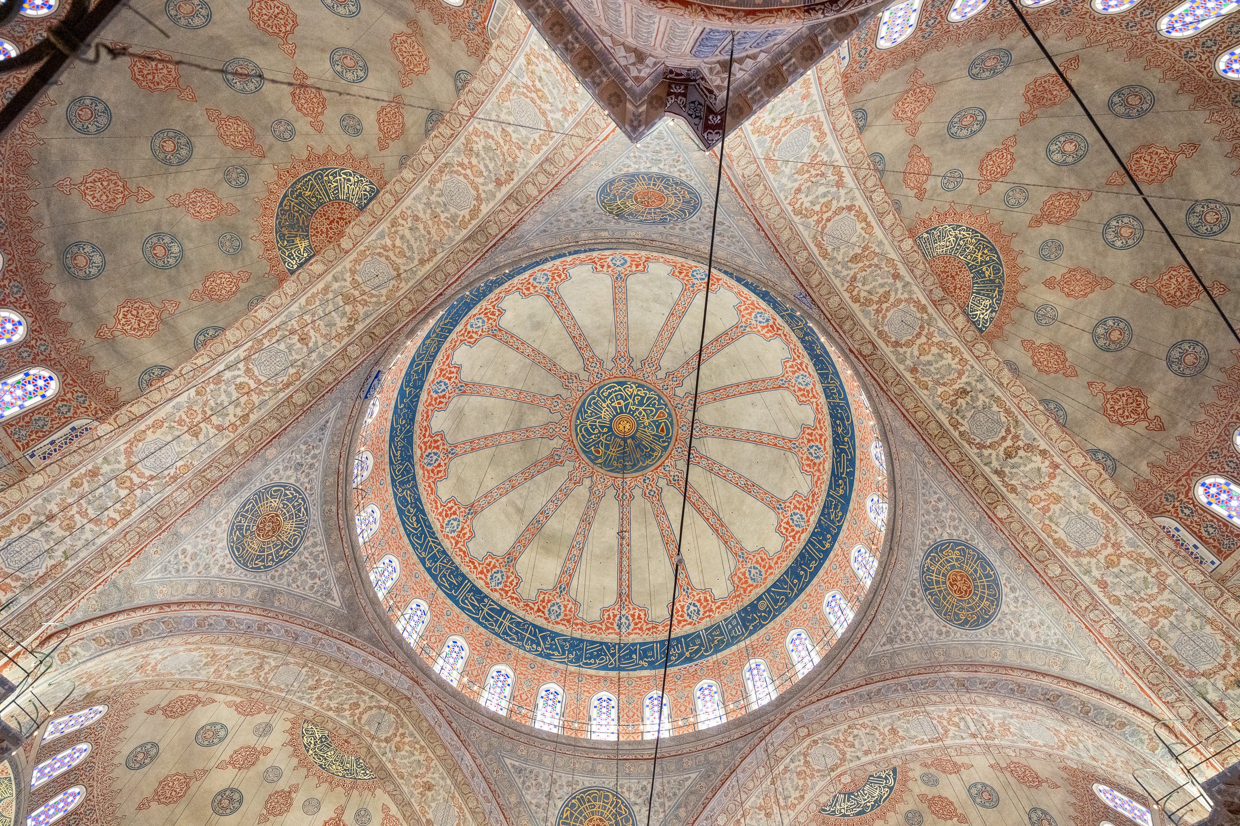 Historic mosque ceiling featuring painted ornamentation and a central dome in Istanbul, Turkey.