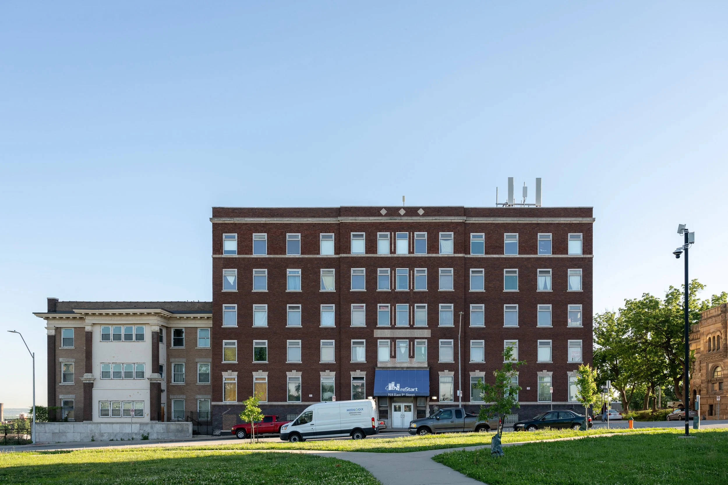 Exterior of a five-story brick office building at dusk with green lawn in foreground