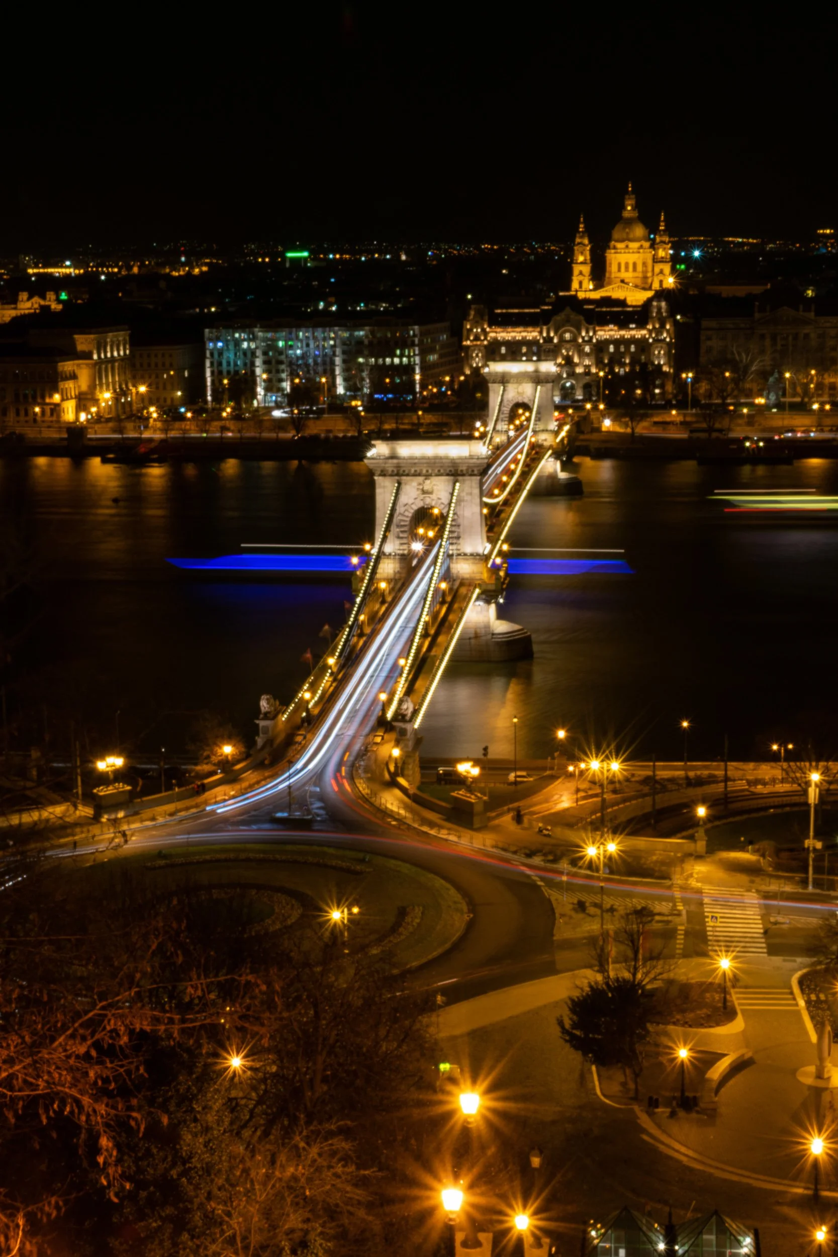 Budapest Chain Bridge at night, long exposure light trails, St. Stephen's Basilica in the background.
