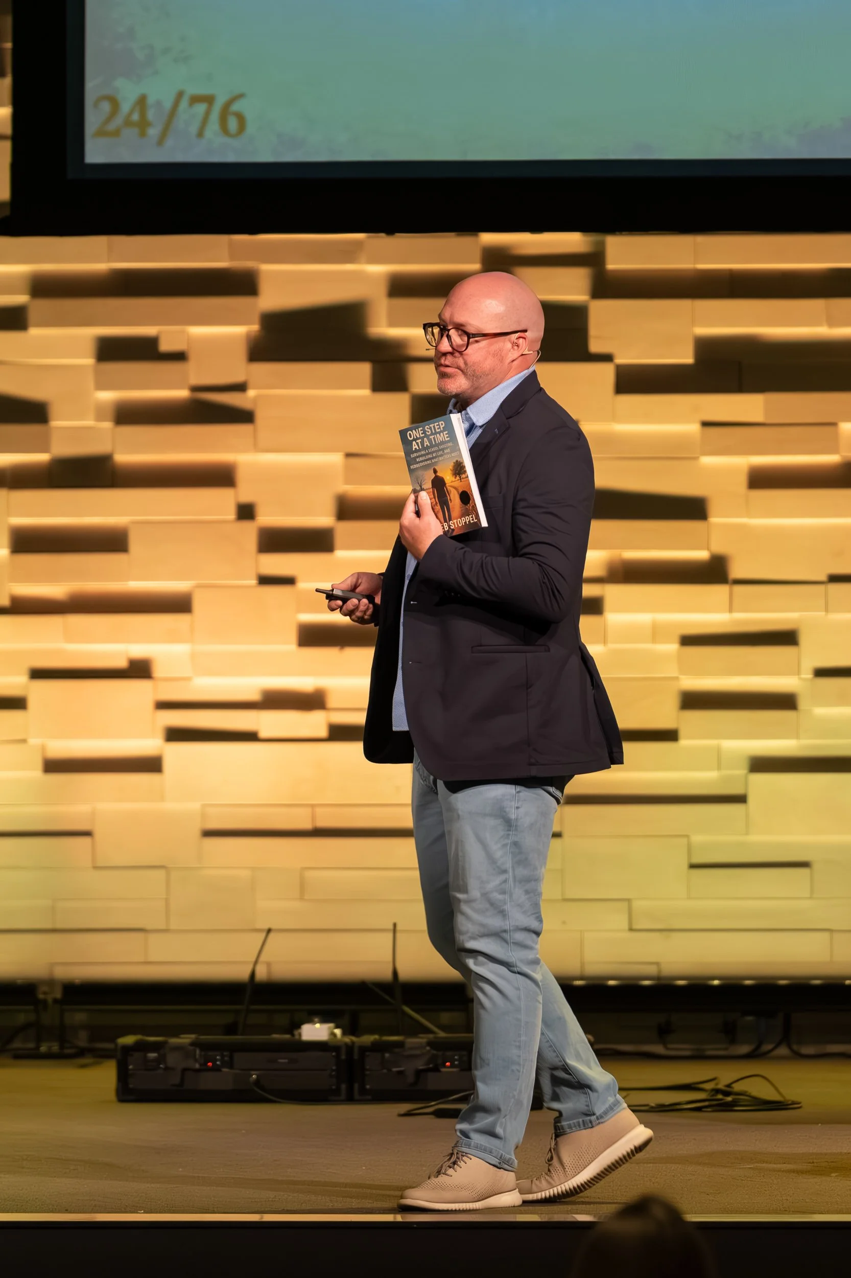 Kaleb Stoppel speaking while holding a copy of his book.