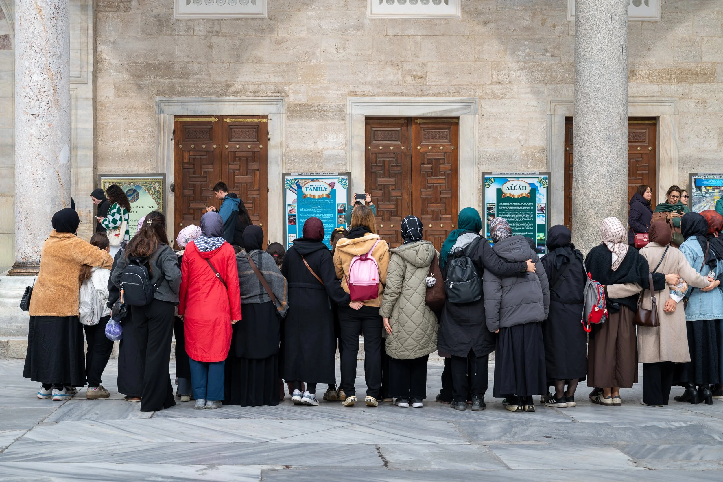 Visitors gather quietly beneath the walls of a historic mosque, offering a glimpse into the rhythms of everyday travel and worship.