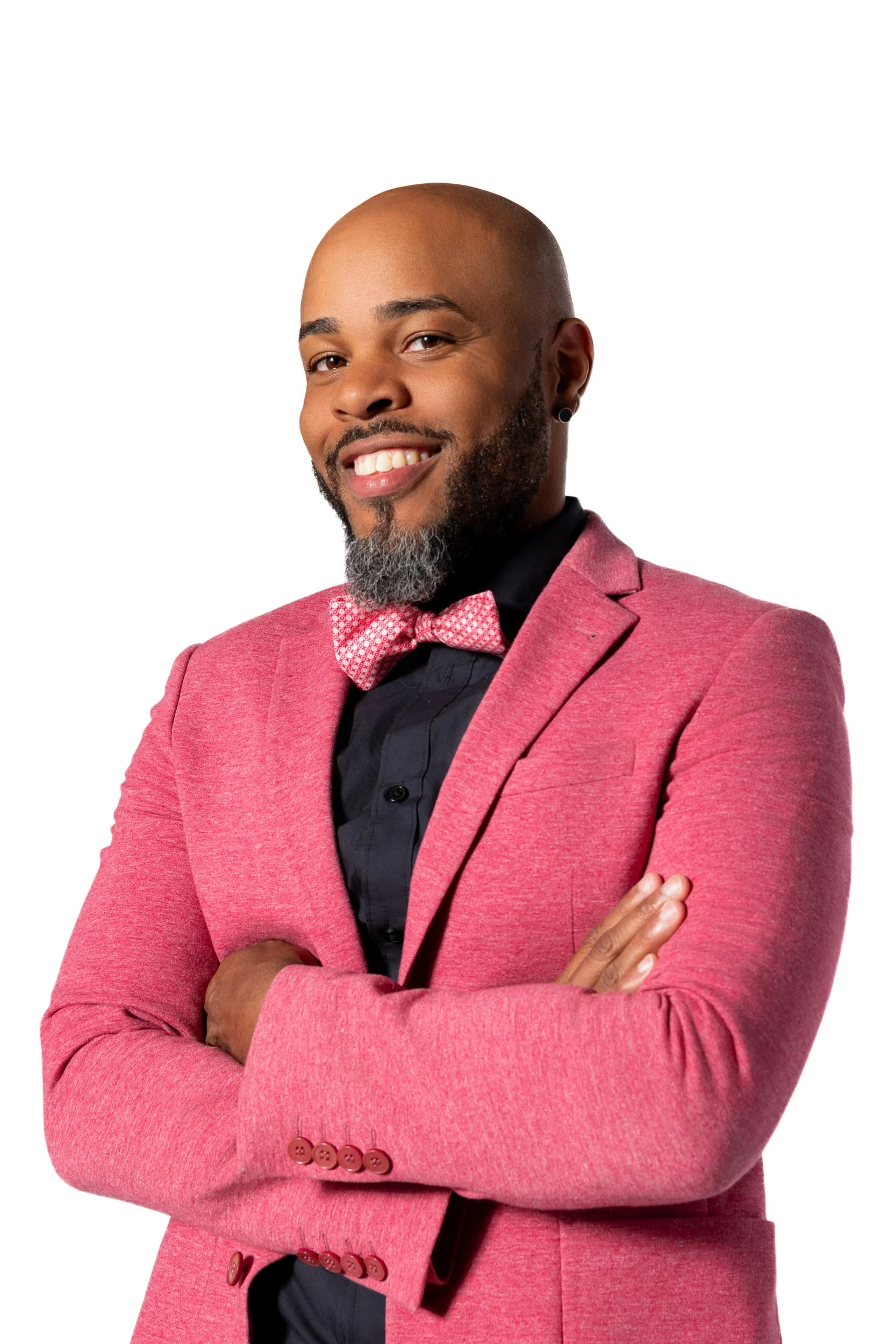 Man in pink blazer and bow tie smiling with arms crossed against white background