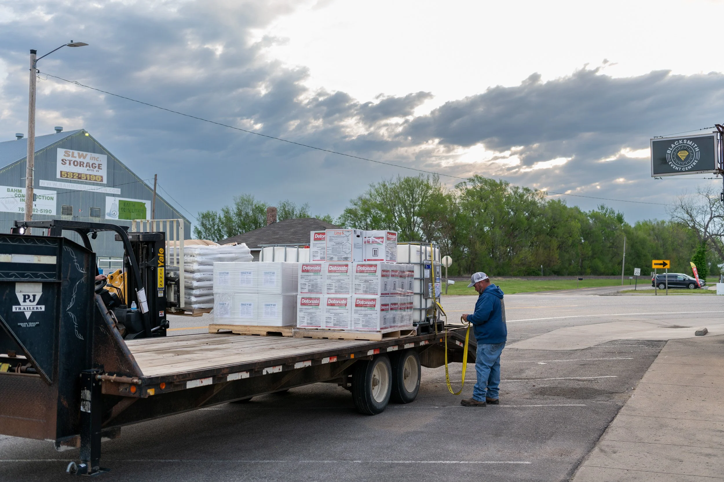 Farmer loading seed and crop supplies onto a flatbed trailer.