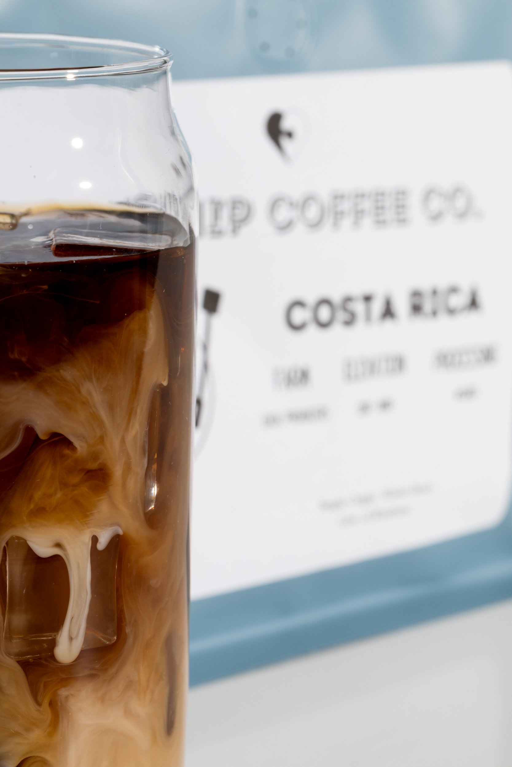 Iced coffee drink with cream swirl against Kinship Coffee Co branding, Kansas City coffee brand photography
