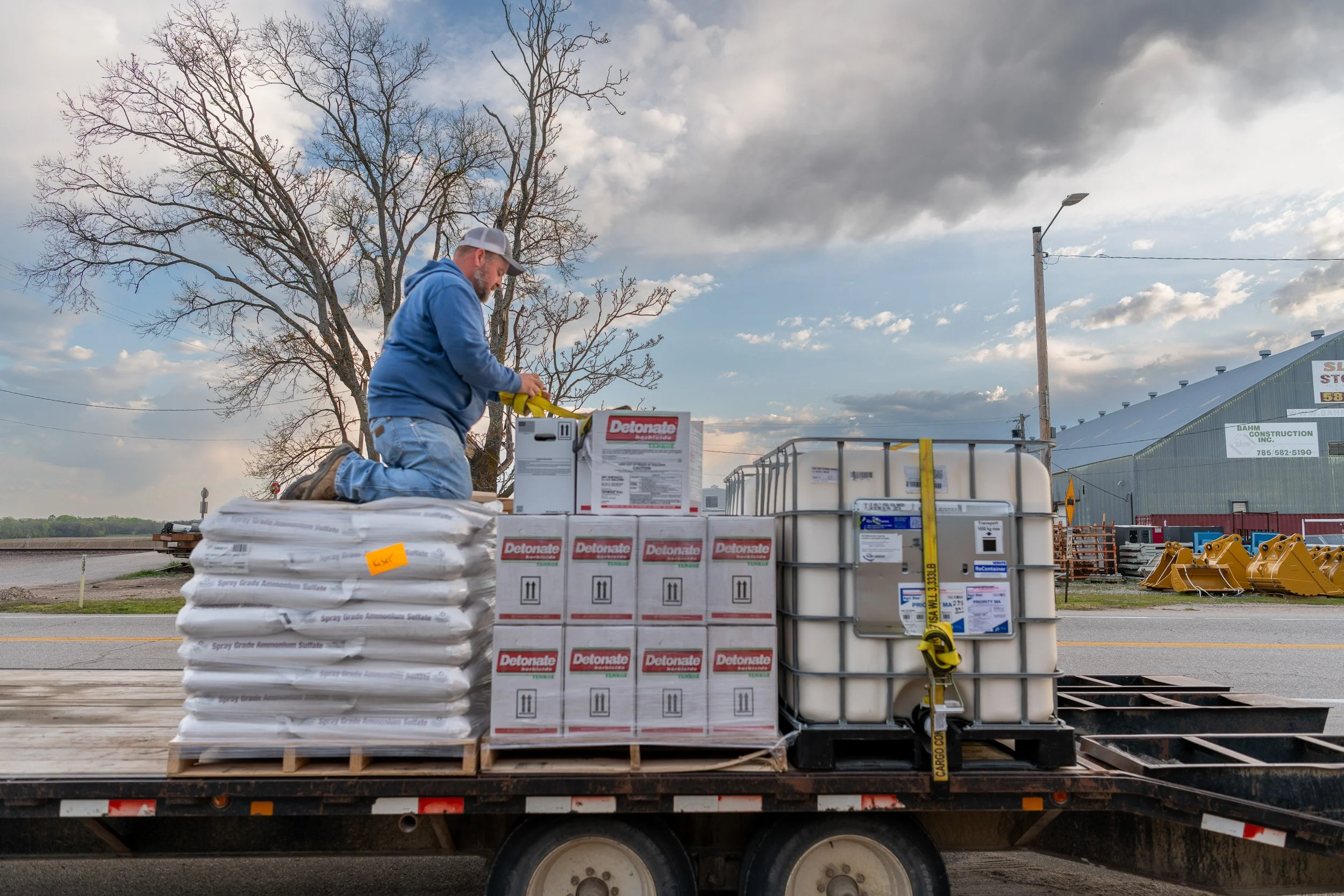 Farmer arranging seed bags and crop supplies on a trailer.