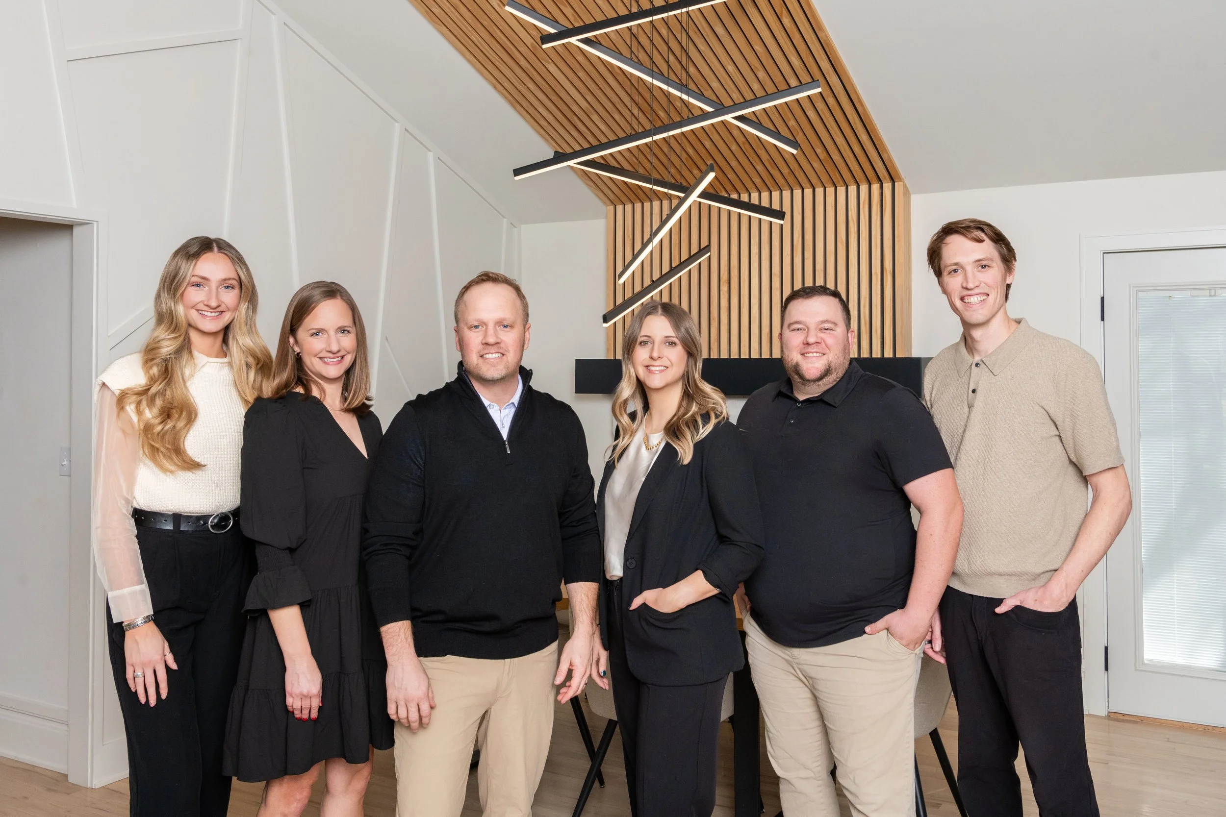 Real estate team portrait session at the Austin Short Group's office in the Kansas City area. The space itself became part of the story: a vaulted wood slat ceiling, angular pendant lighting, and clean architectural geometry that reflects how the tea