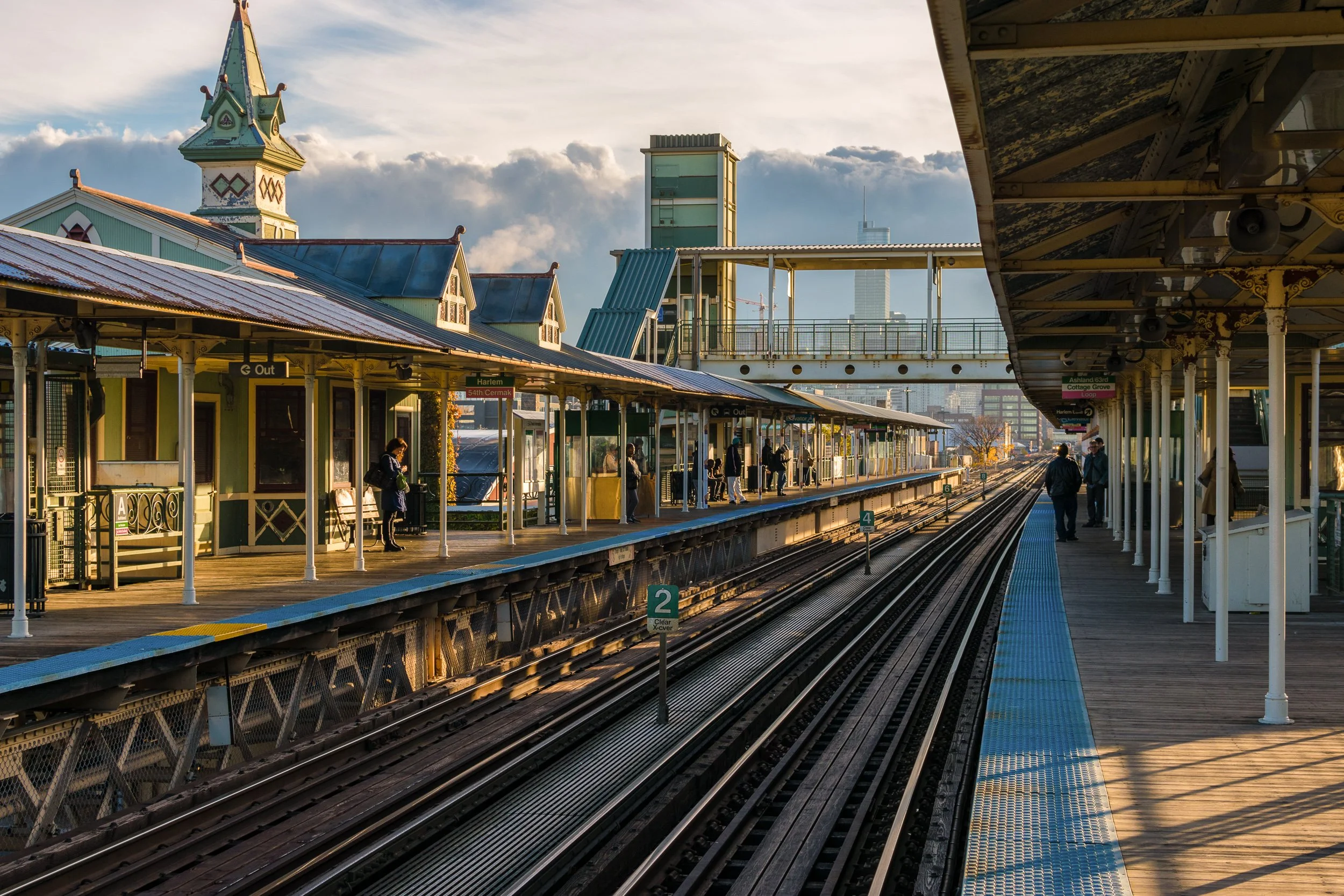 Chicago L train elevated station platform with Victorian-style station building and open sky.