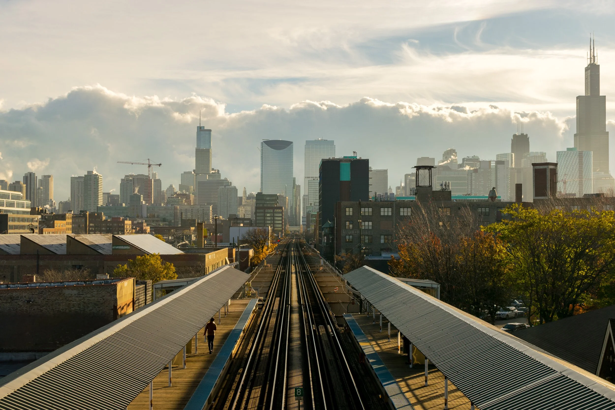 Chicago L elevated train tracks with strong leading lines toward the downtown skyline at golden hour.