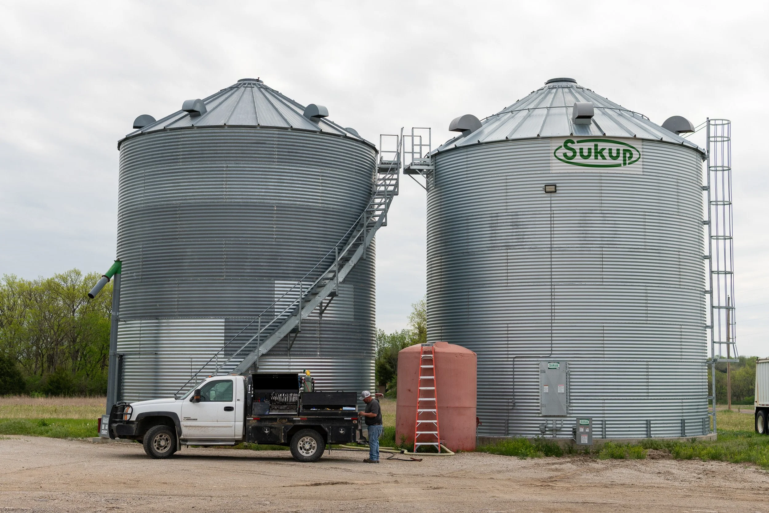 Grain bins beside a farm truck and storage tanks.
