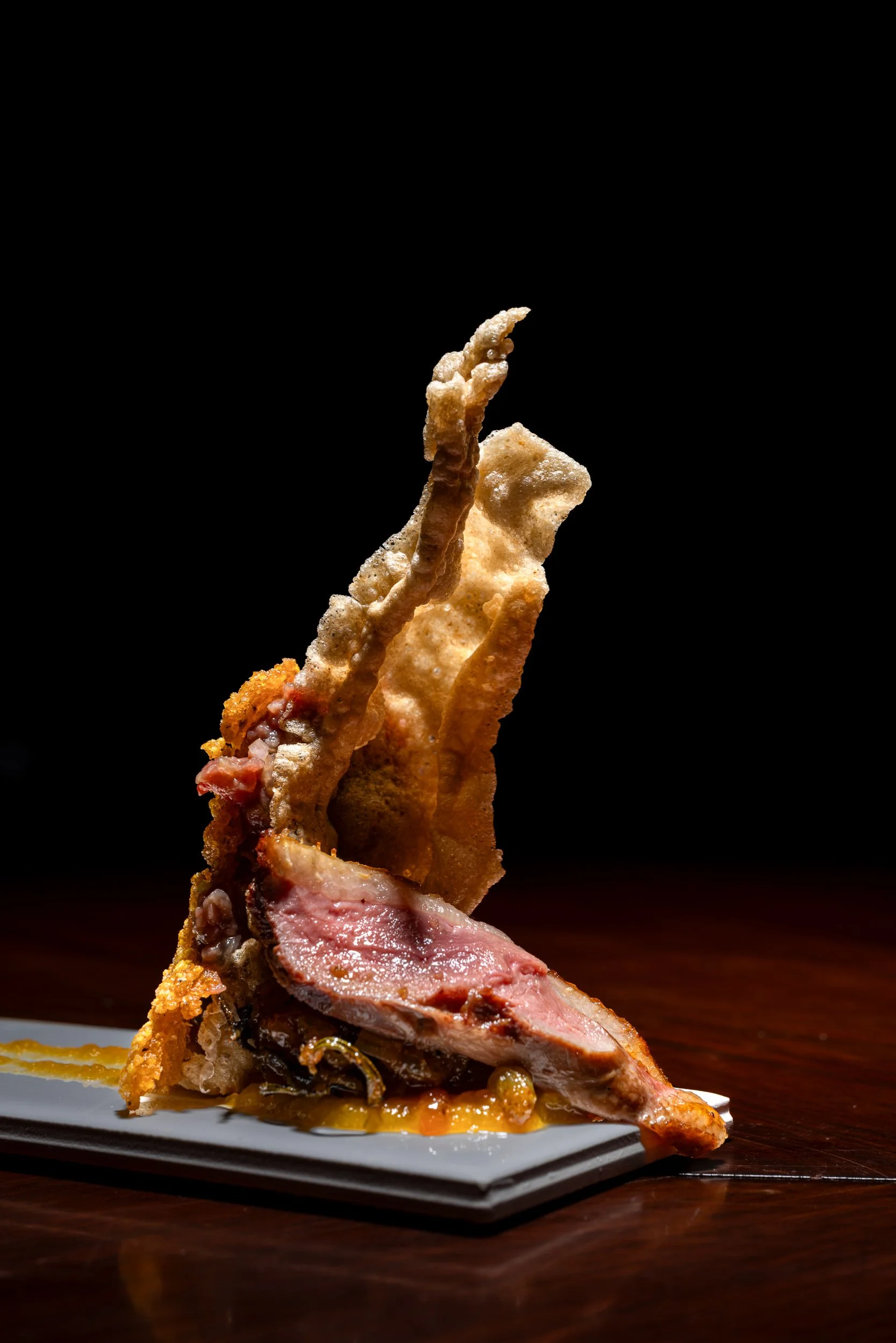 Sculptural bone-in meat on slate against dark background, fine dining culinary photography Kansas City