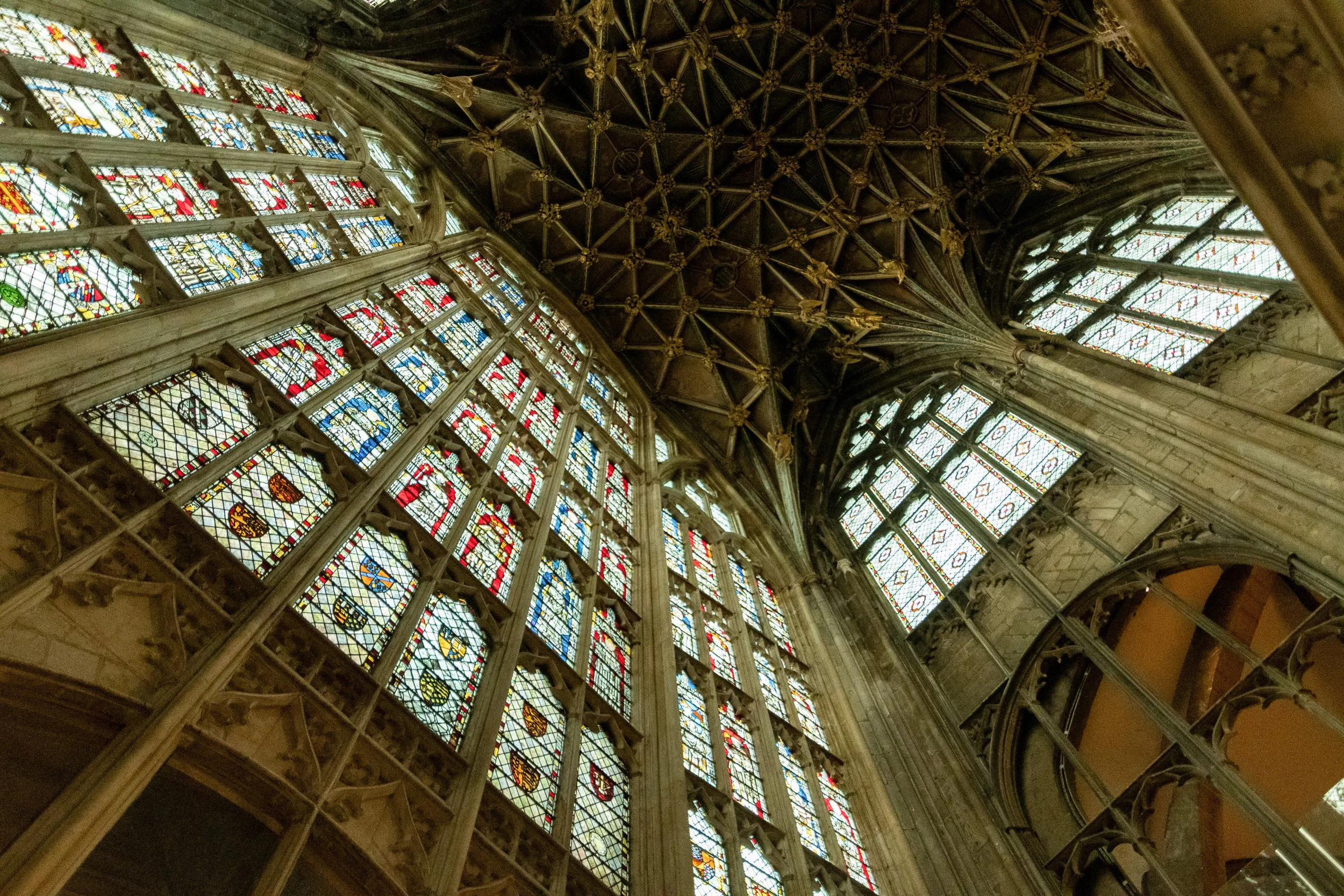 Gothic cathedral ceiling with stained glass windows and intricate stone vaulting, England.